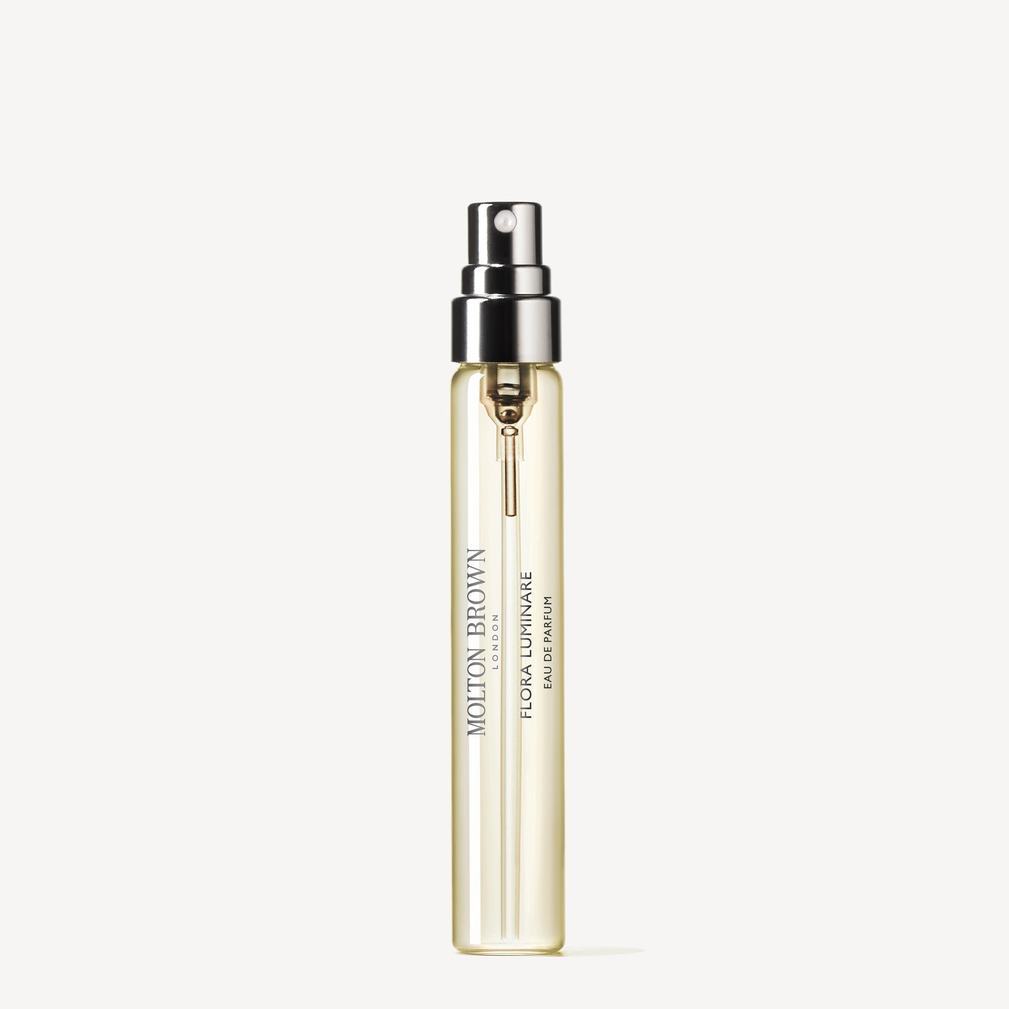 A slim, clear 7.5ml travel spray bottle of MoltonBrown Nederlands Flora Luminare Eau de Parfum, with a silver and black nozzle and delicate jasmijn notes, stands upright on a white background.