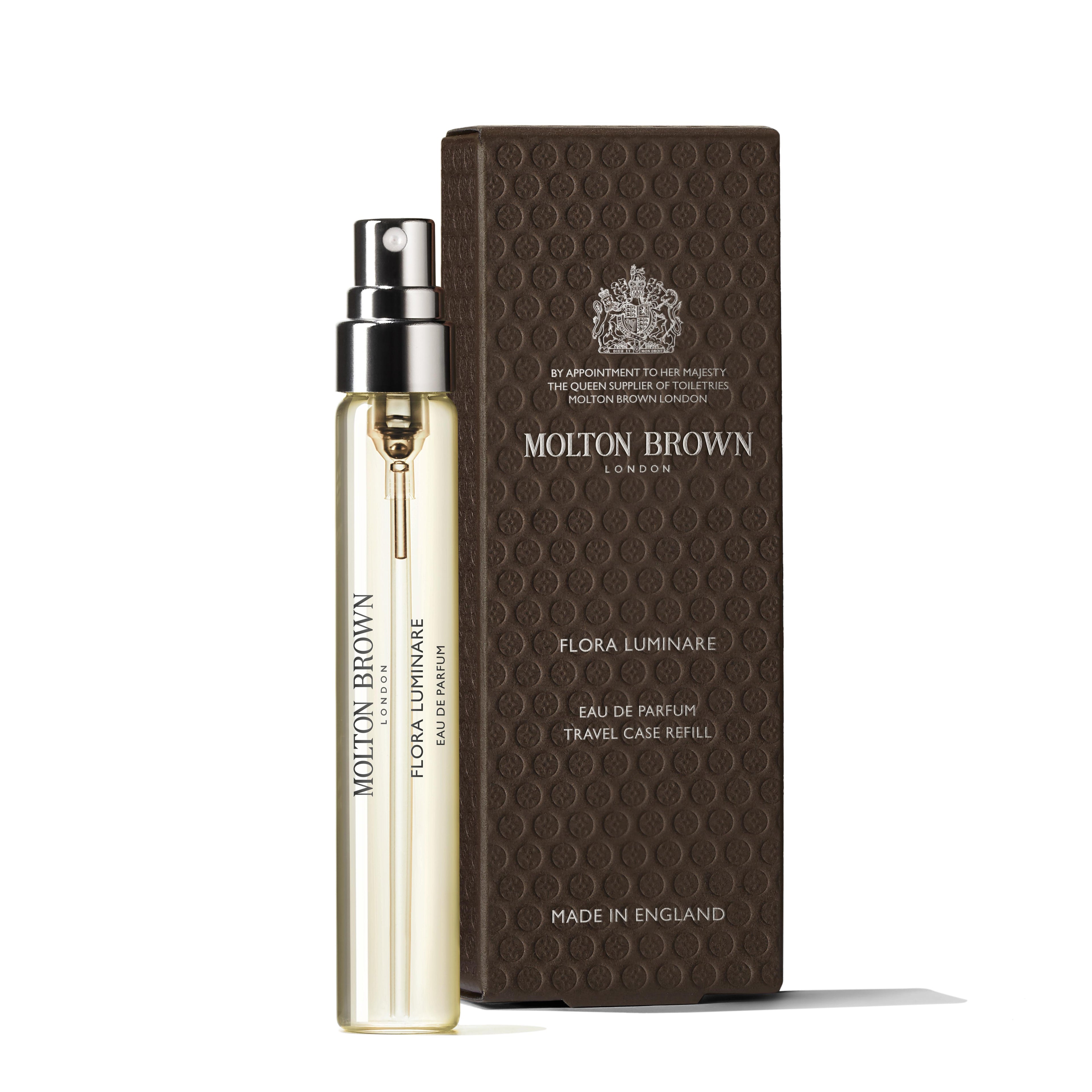 A MoltonBrown Nederlands Flora Luminare Eau de Parfum Reiskoffer Navulling 7.5ml stands upright next to its textured brown box—clear bottle with black text and branded packaging, perfectly paired with jasmijn handzeep.