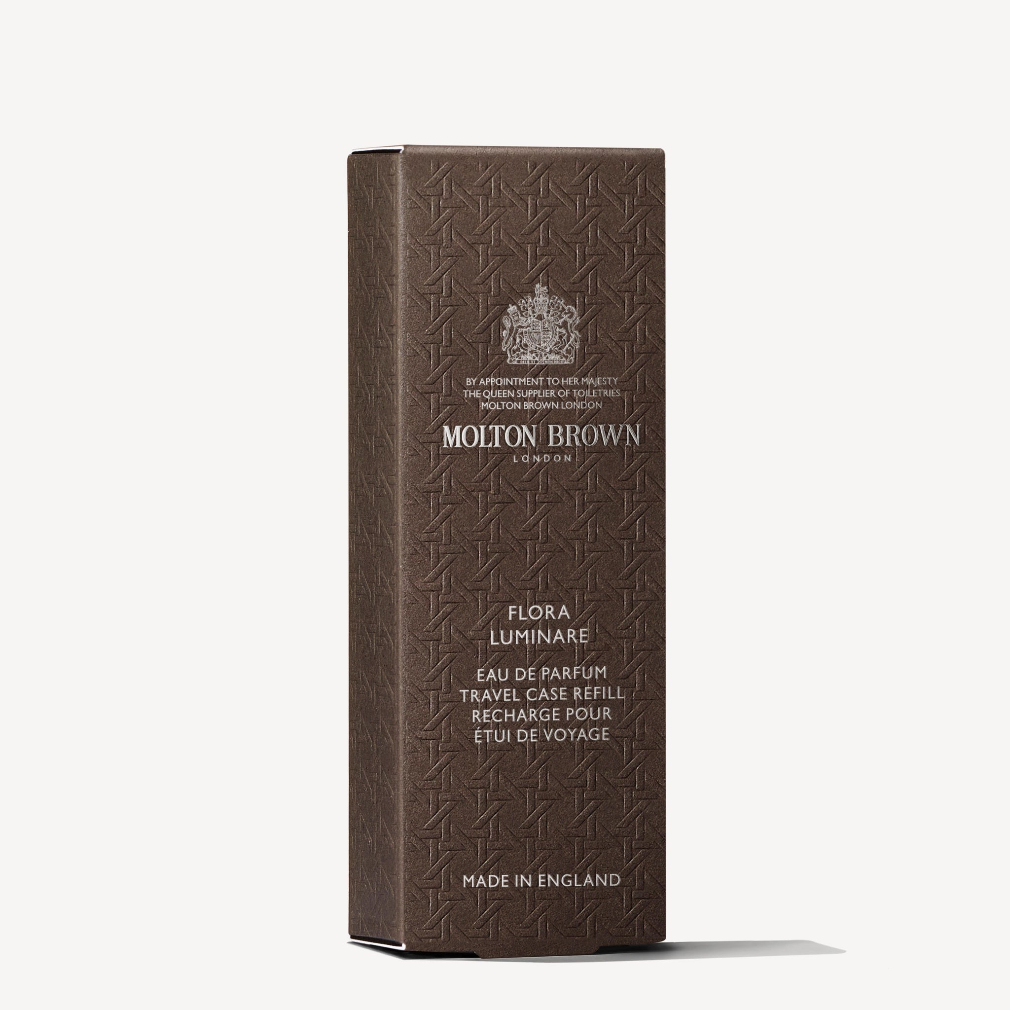A brown textured box stands upright, displaying the MoltonBrown Nederlands logo and "Flora Luminare Eau de Parfum Reiskoffer Navulling 7.5ml," with jasmijn notes and "Made in England" in silver text.