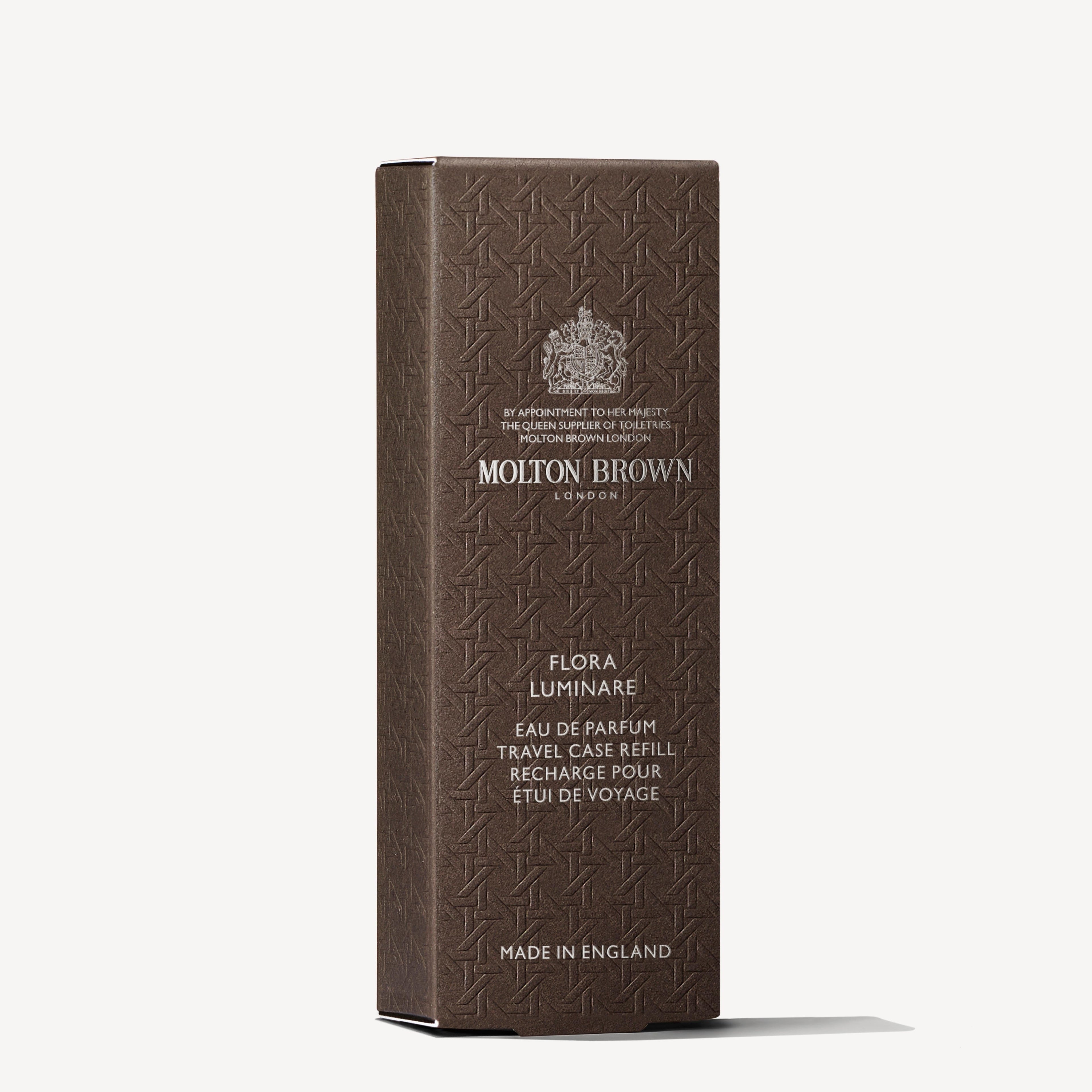 A brown textured box stands upright, displaying the MoltonBrown Nederlands logo and "Flora Luminare Eau de Parfum Reiskoffer Navulling 7.5ml," with jasmijn notes and "Made in England" in silver text.