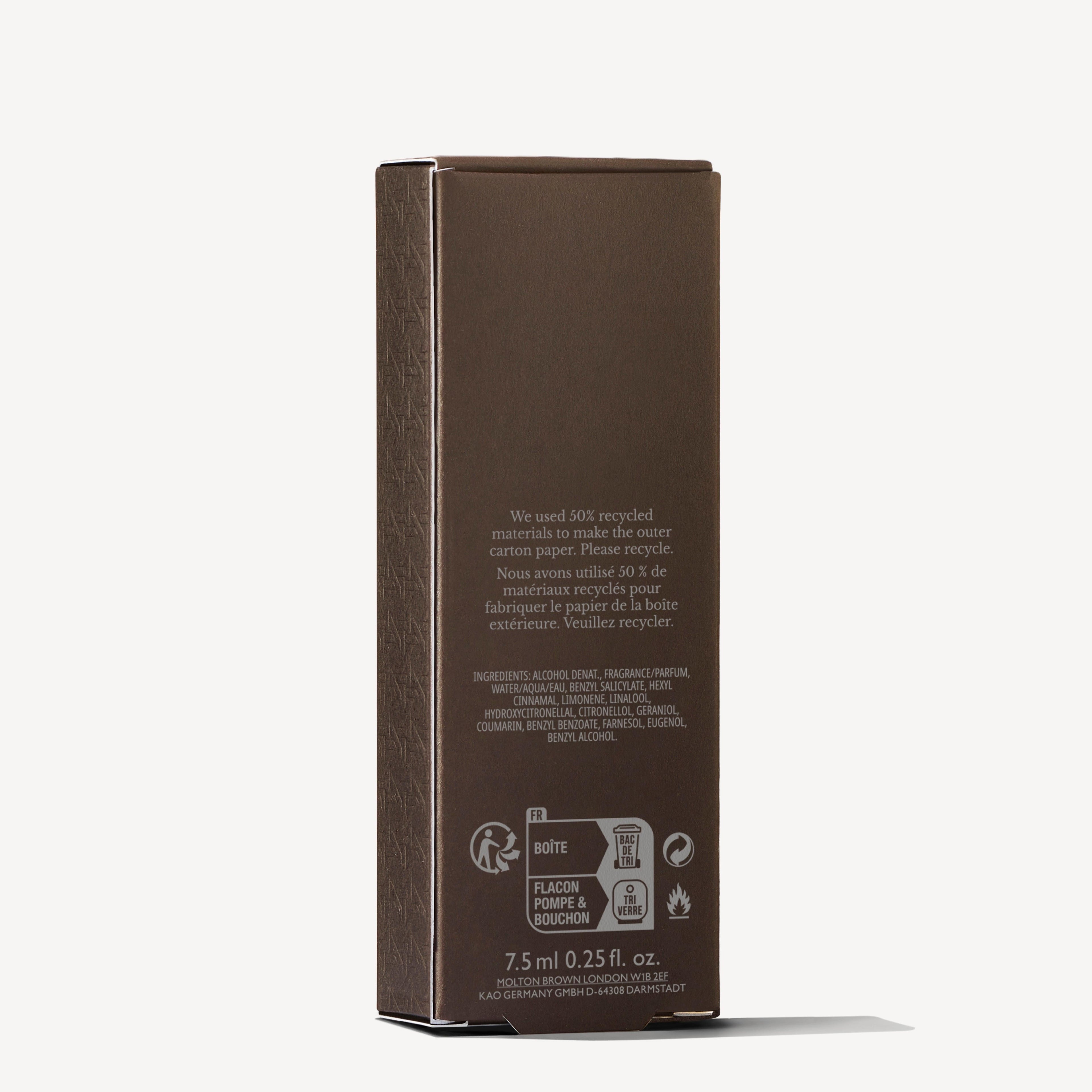 A rectangular brown Flora Luminare Eau de Parfum Reiskoffer Navulling 7.5ml box by MoltonBrown Nederlands stands upright on a white background, featuring eco icons, text about recycled materials, and a shadow to the left.