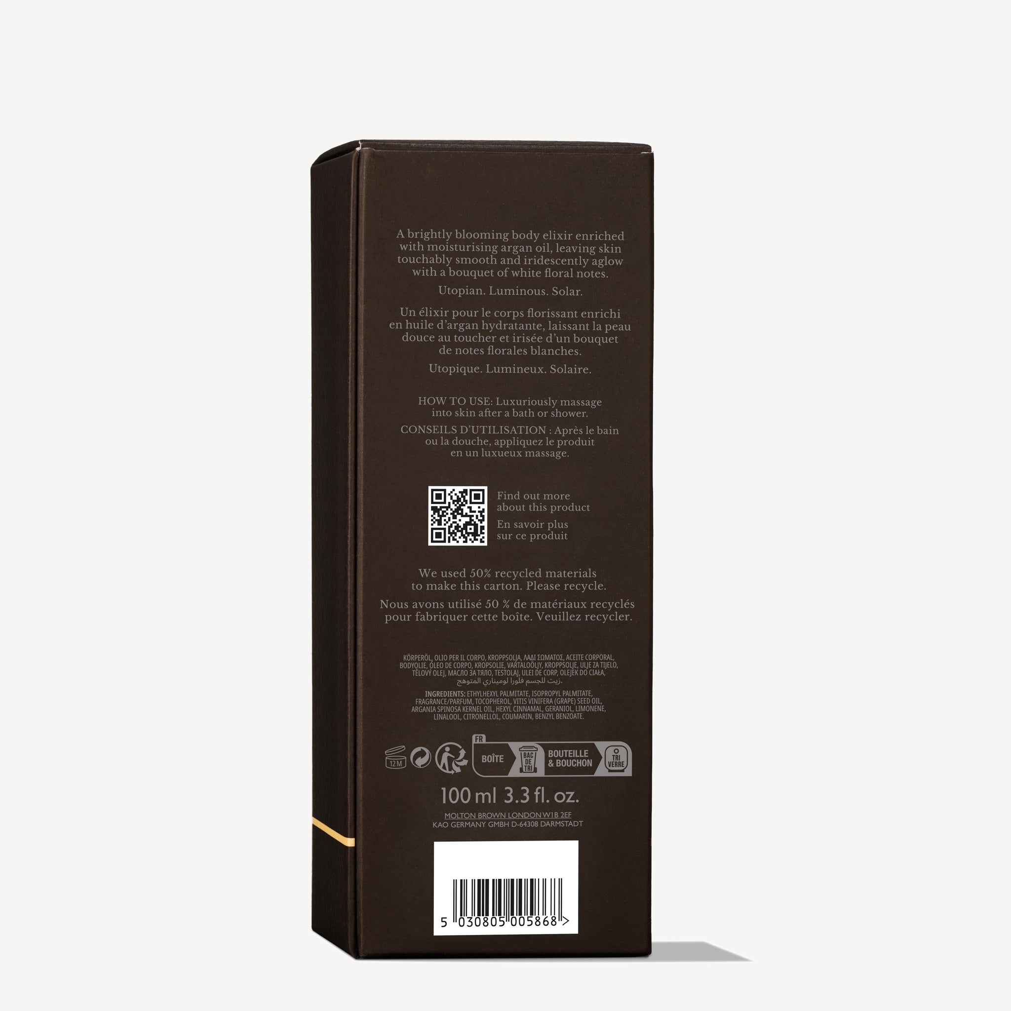 A dark brown rectangular Flora Luminare Glowing Lichaamsolie 100ml box by MoltonBrown Nederlands stands upright, showing English and French info, witte moerbei extract, jasmijn, a QR code, barcode, and size details—ideal for body oil use.