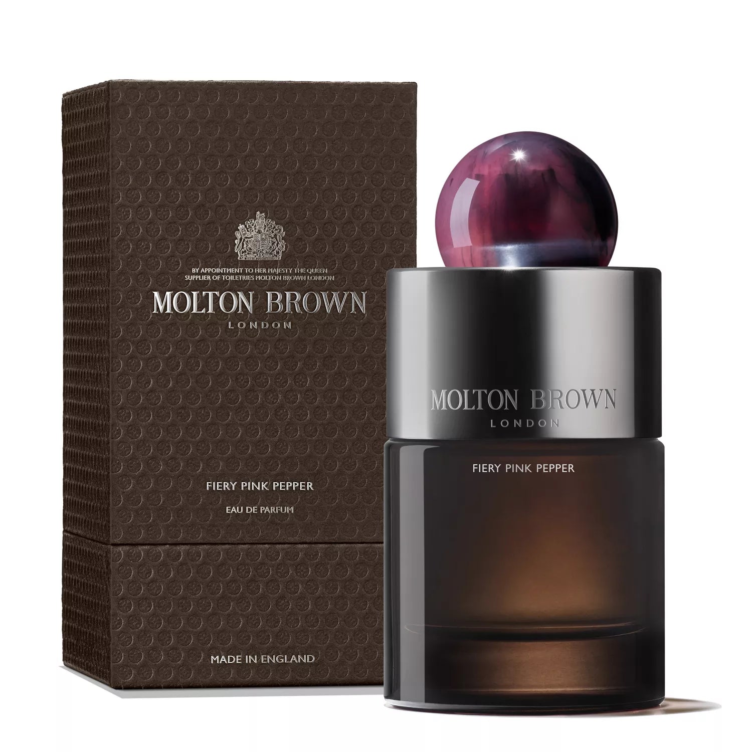 A MoltonBrown Nederlands Fiery Pink Pepper Eau de Parfum 100ml with a pink marbled cap appears beside its textured brown box, both displaying the brand and product details in silver, evoking cedarwood notes.