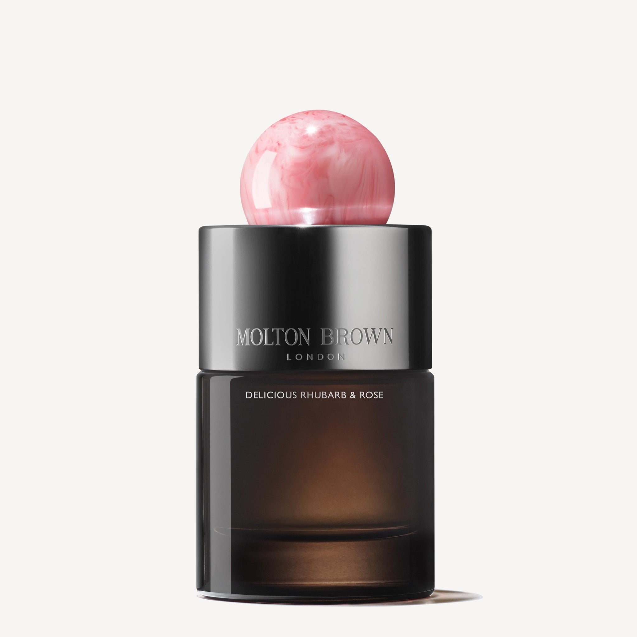A 100ml bottle of MoltonBrown Nederlands Delicious Rhubarb & Rose Eau de Parfum features a round pink marbled cap, dark semi-transparent base, and jasmijn notes, shown against a white background.
