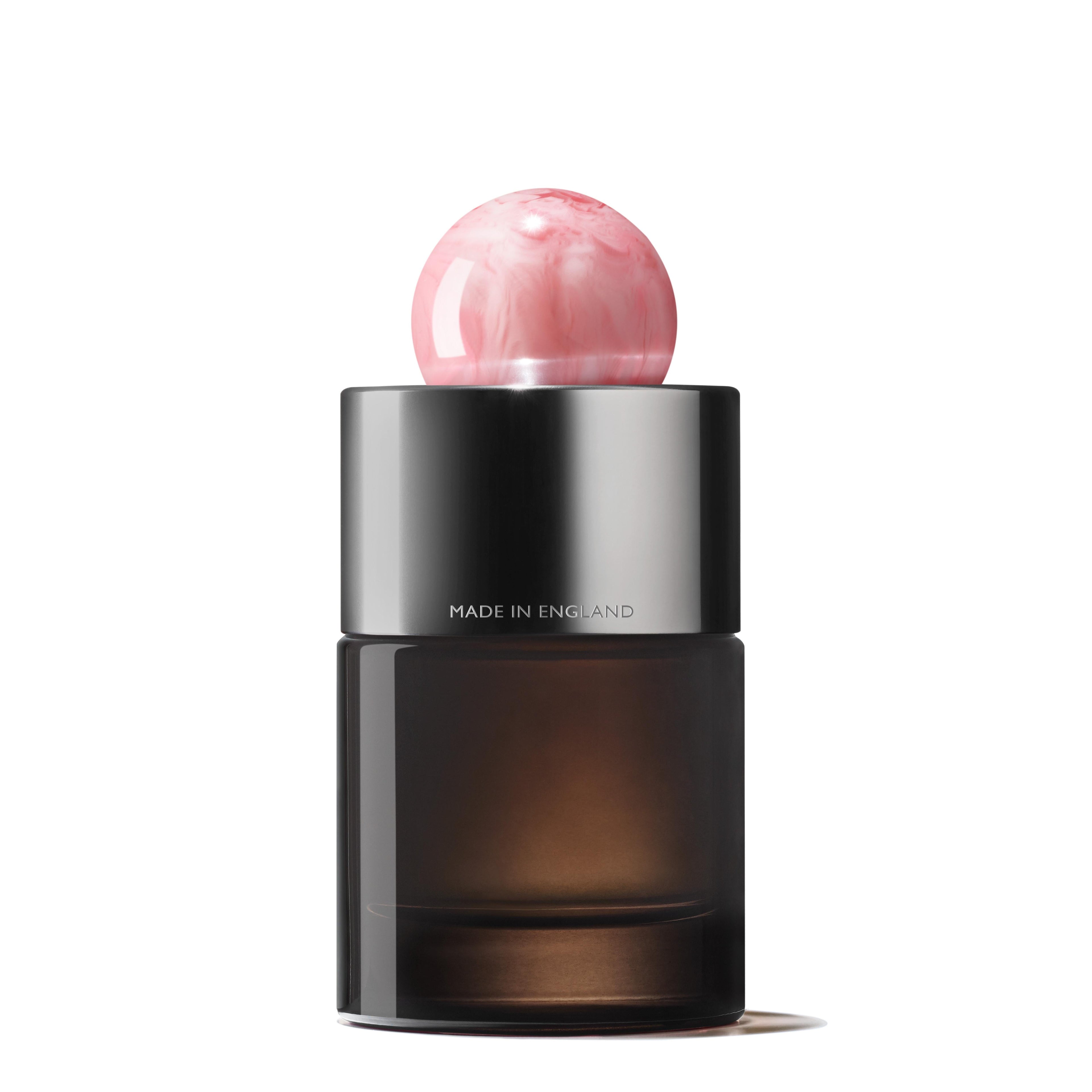 MoltonBrown Nederlands Delicious Rhubarb & Rose Eau de Parfum 100ml comes in a sleek dark glass bottle with a metallic silver collar marked "MADE IN ENGLAND" and a pink marbled cap. Contains jasmijn and witte moerbei extract. White backdrop.