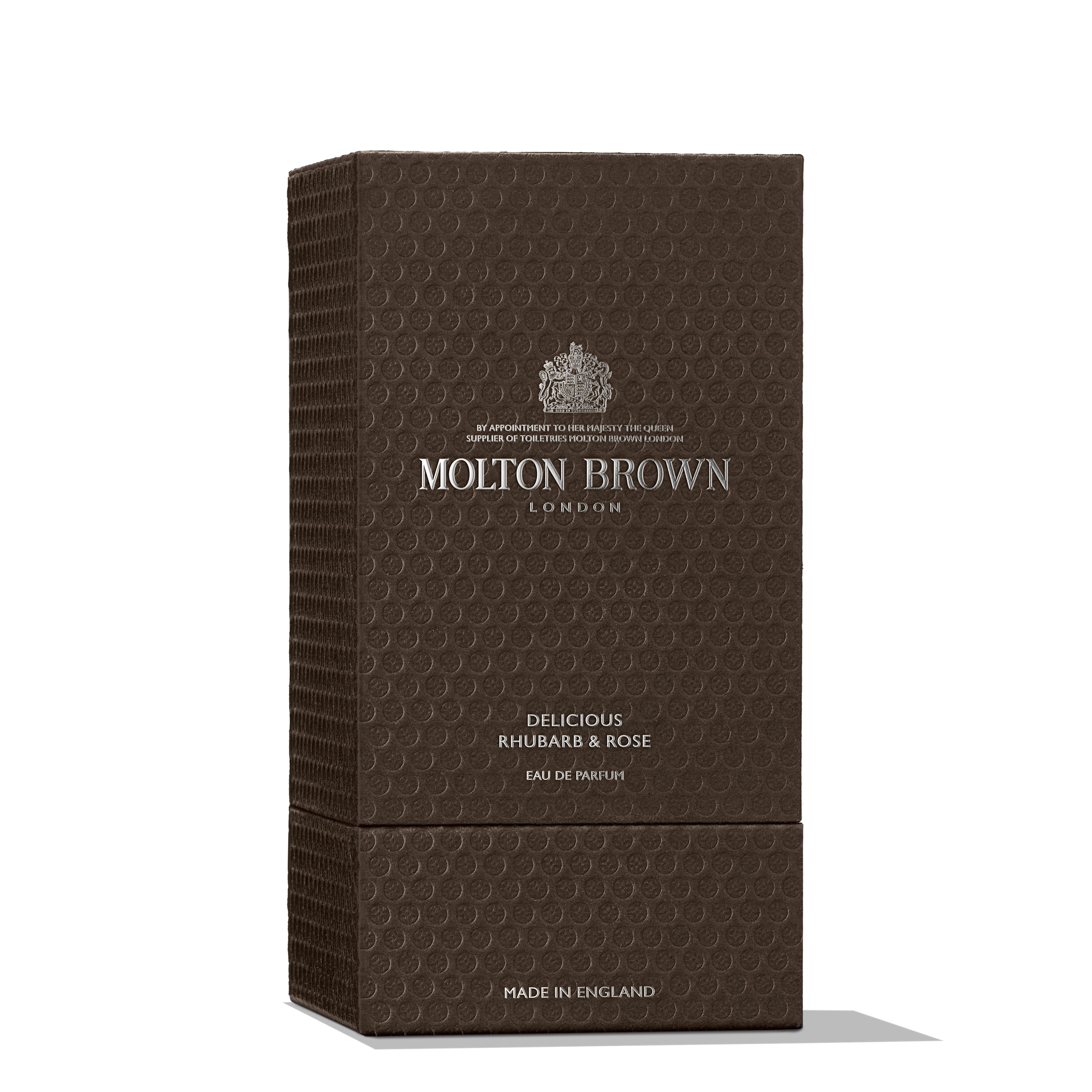 A textured dark brown rectangular box of MoltonBrown Nederlands Delicious Rhubarb & Rose Eau de Parfum 100ml, with silver embossed text and logo, is photographed on a white background—ideal alongside their handzeep met witte moerbei-extract.