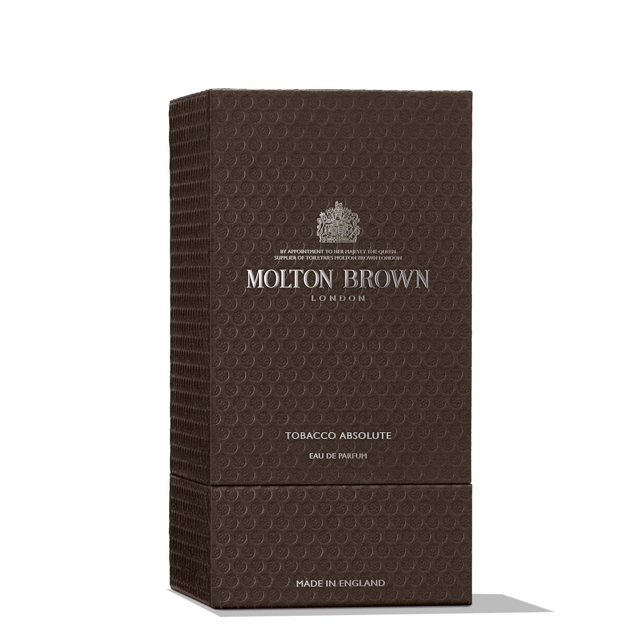 A rectangular, textured dark brown box with the MoltonBrown Nederlands logo in silver. Labeled Tobacco Absolute Eau de Parfum 100ml, it blends cederhout and sinaasappelbloesem notes. Made in England.