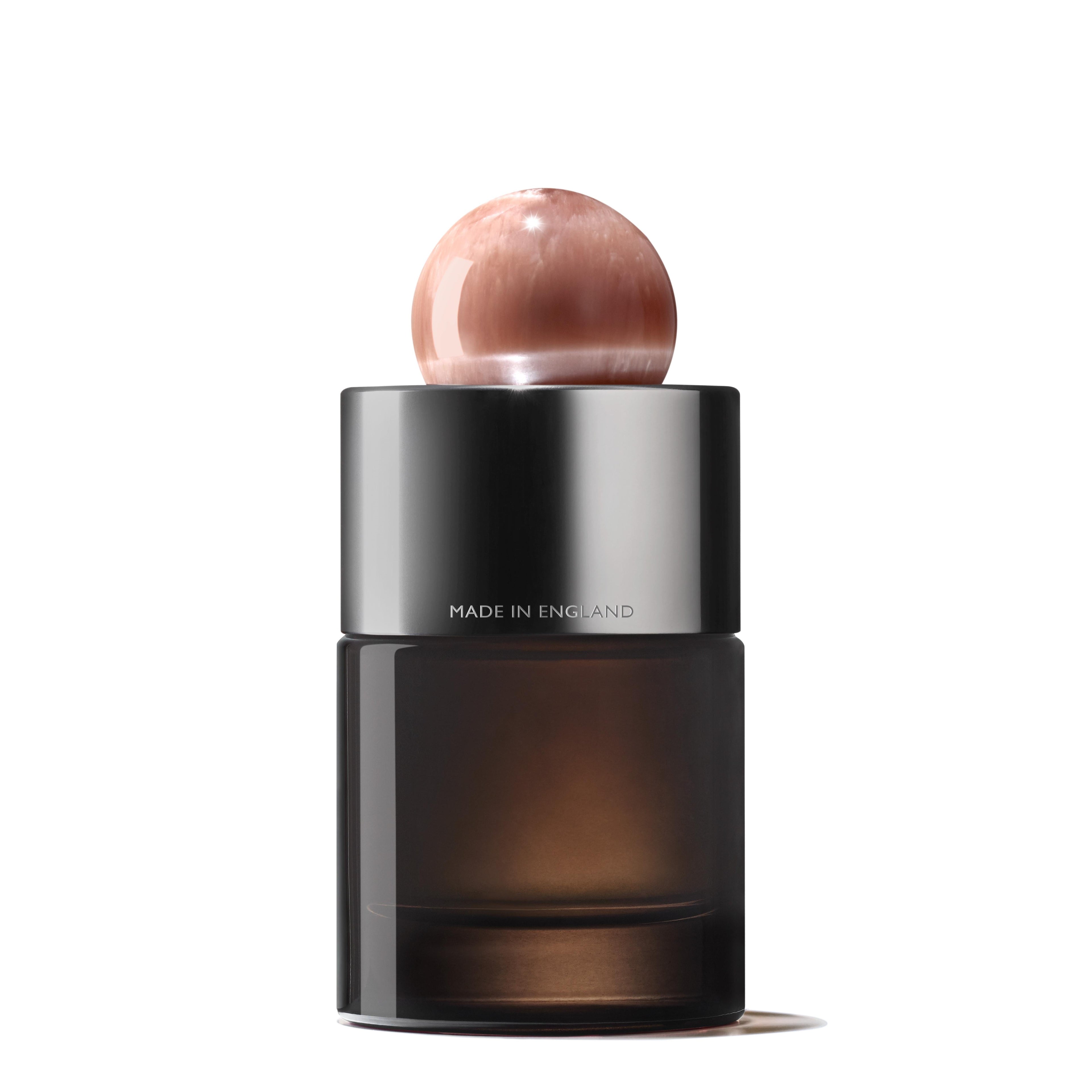 The MoltonBrown Nederlands Heavenly Gingerlily Eau de Parfum 100ml features a sleek dark glass bottle with a shiny metallic collar engraved "MADE IN ENGLAND" and a polished rose-toned cap, elegantly posed against a white background.