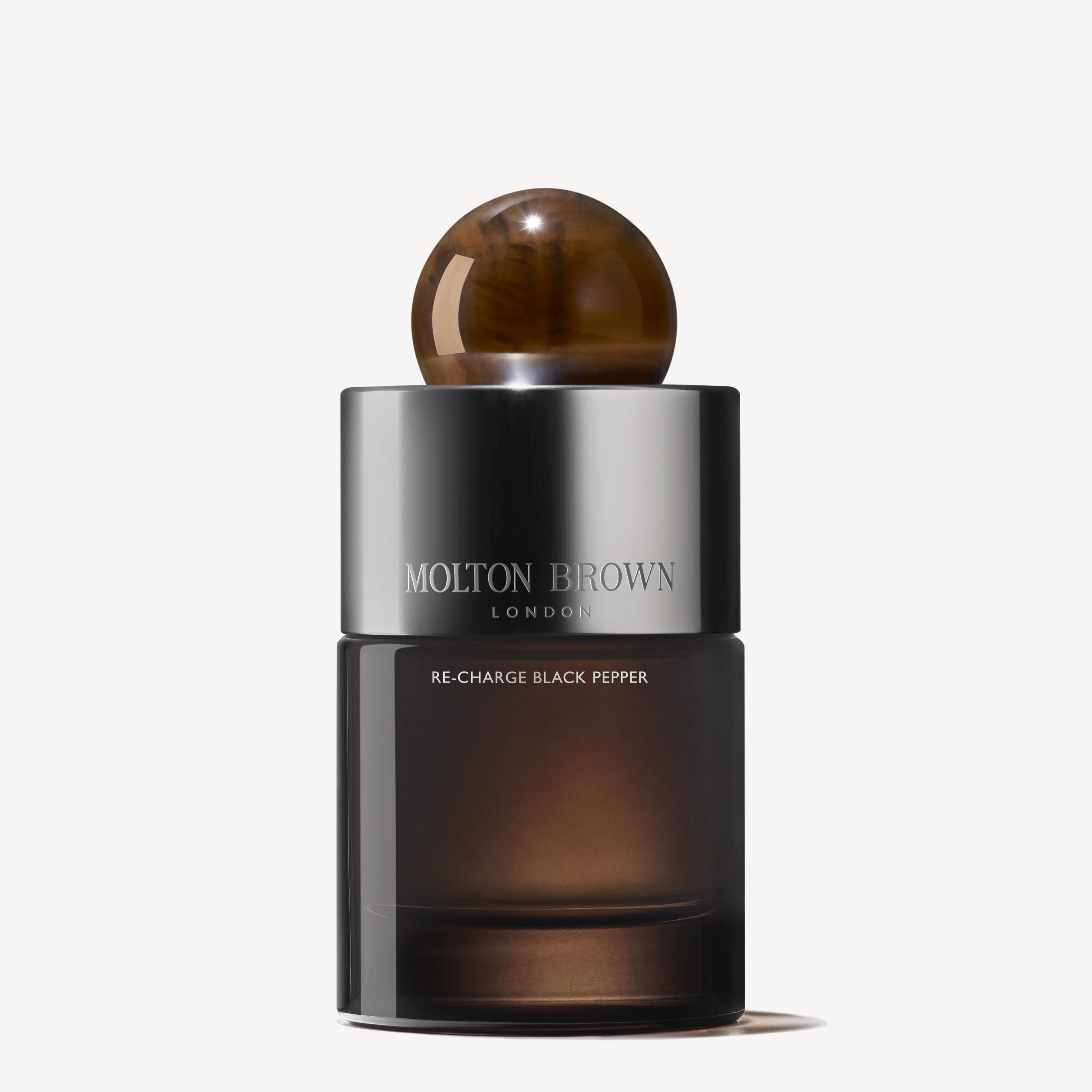 A 100ml bottle of MoltonBrown Nederlands Re-charge Black Pepper Eau de Parfum features a dark gradient glass, metallic silver branded band, round brown cap, and is subtly enhanced with notes of sandelhout.
