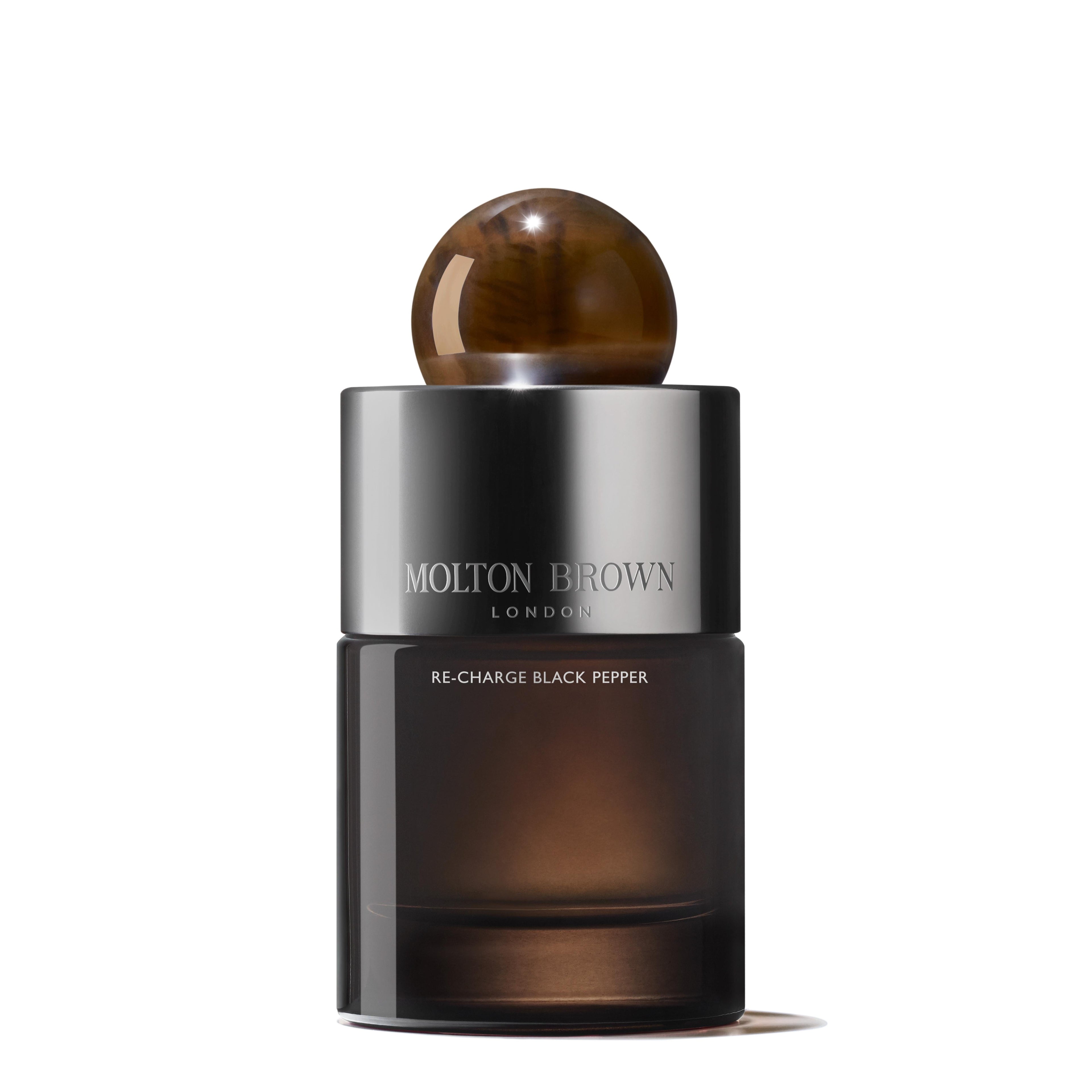 A sleek, dark brown 100ml bottle of MoltonBrown Nederlands Re-charge Black Pepper Eau de Parfum features a shiny metallic label, round brown cap, and the product name displayed on the front.