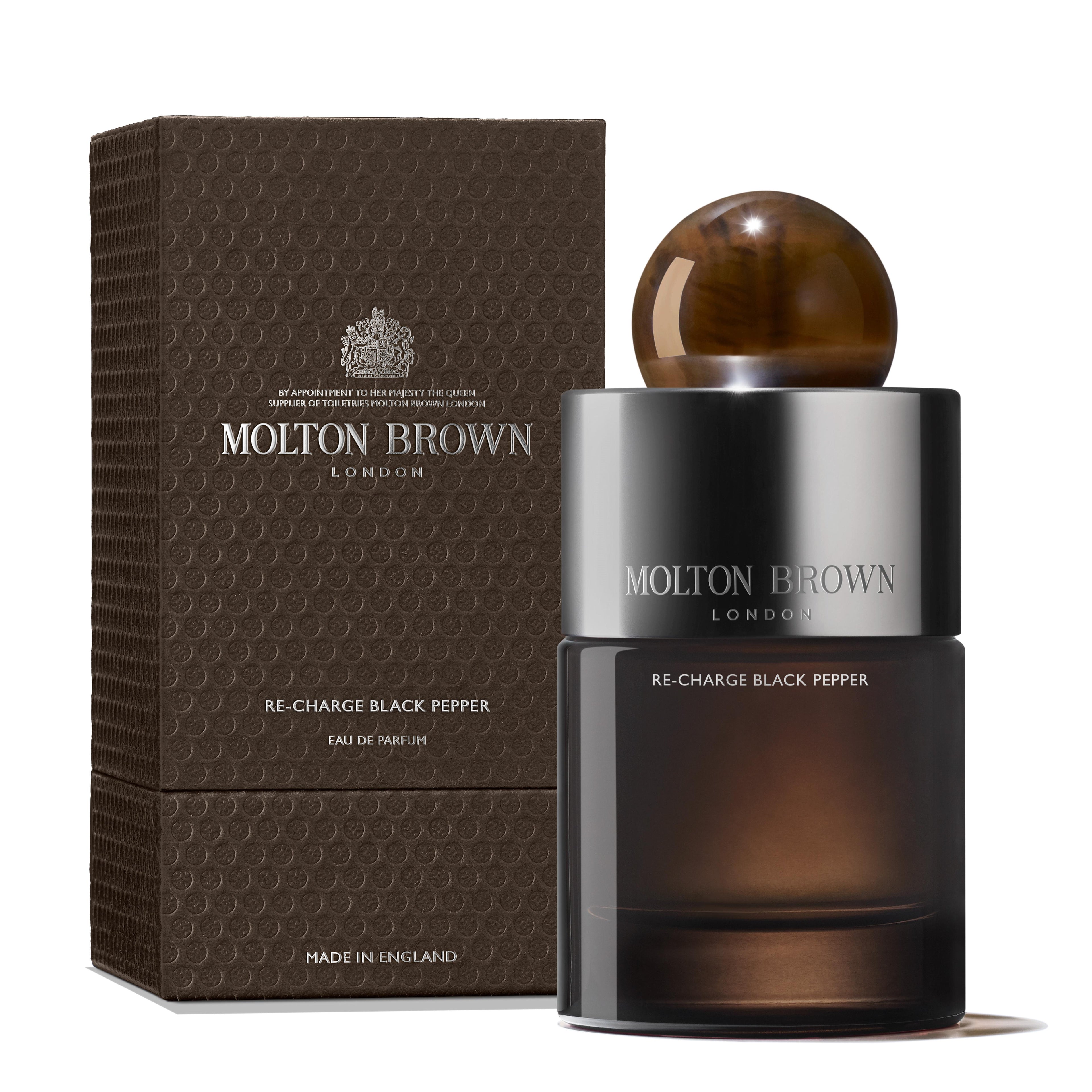 A 100ml bottle of MoltonBrown Nederlands Re-charge Black Pepper Eau de Parfum stands beside its textured brown box, with a black bottle and brown spherical cap, featuring silver branding and fragrance name.