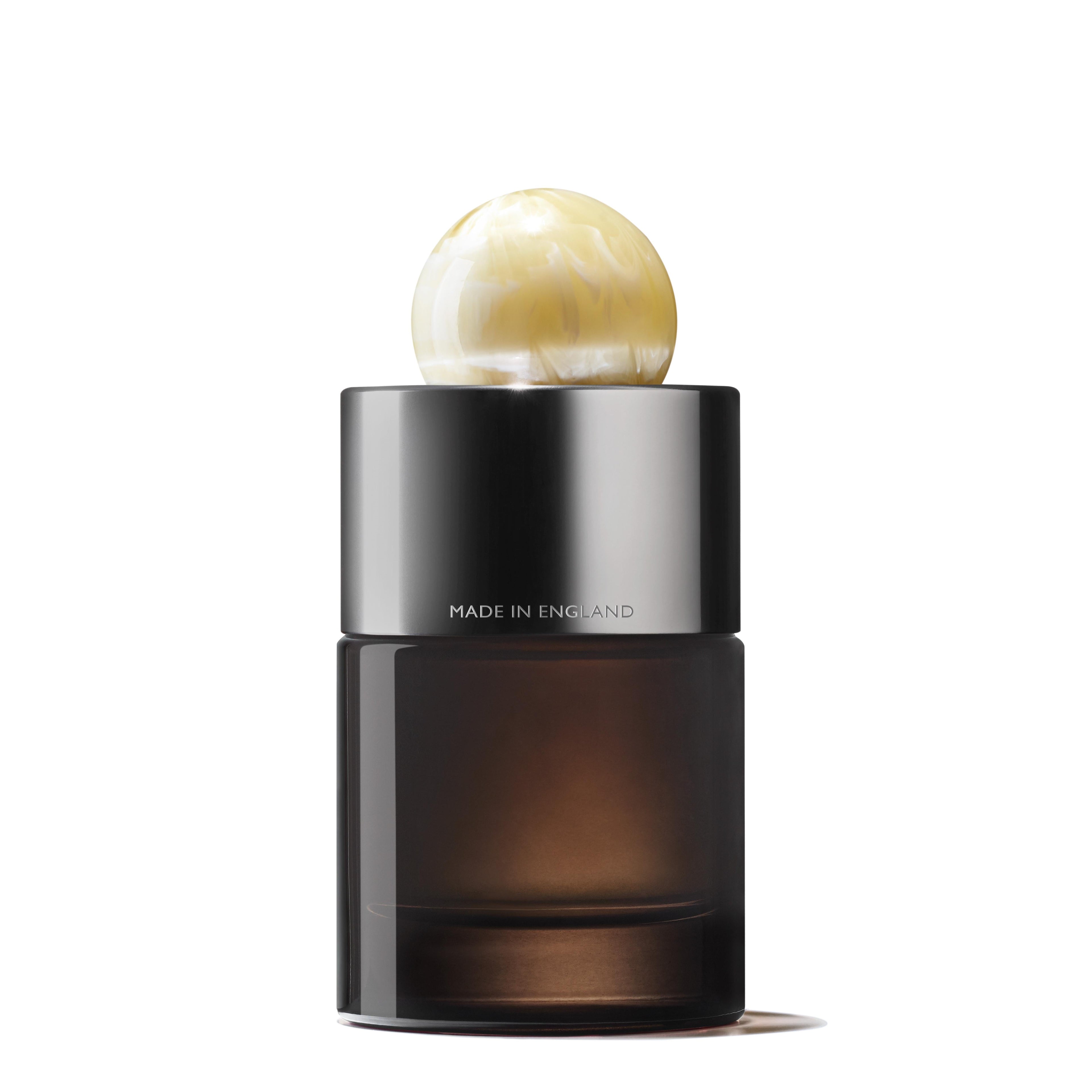 The Orange & Bergamot Eau de Parfum 100ml by MoltonBrown Nederlands features a dark glass bottle, shiny silver neck band printed with "MADE IN ENGLAND," and a marbled ivory cap; cederhout and patchouli notes enrich its allure.