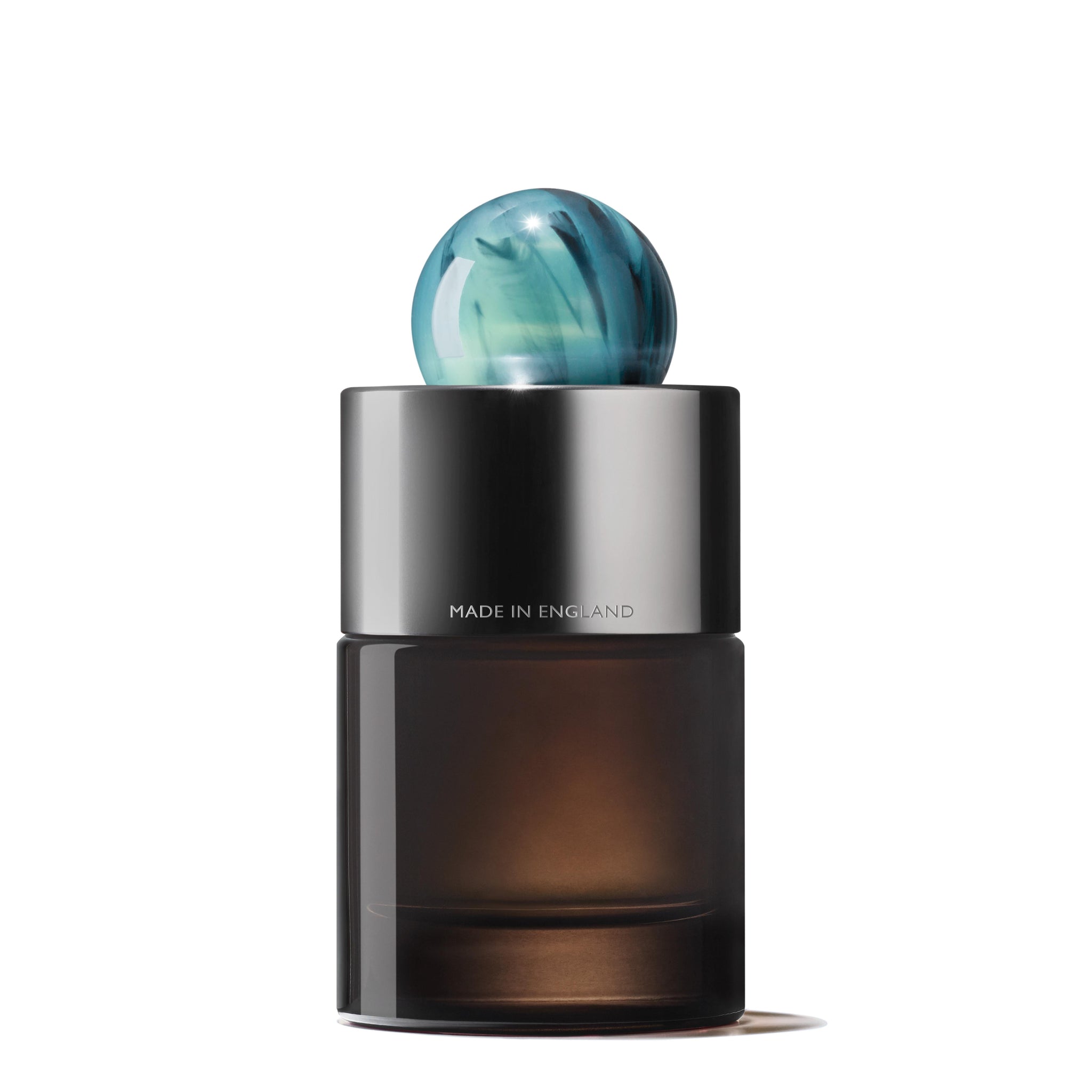 A sleek, dark glass bottle of MoltonBrown Nederlands Coastal Cypress & Sea Fennel Eau de Parfum 100ml features a metallic collar engraved with "MADE IN ENGLAND" and a marbled blue-green cap, set against a white background for an elegant allure.