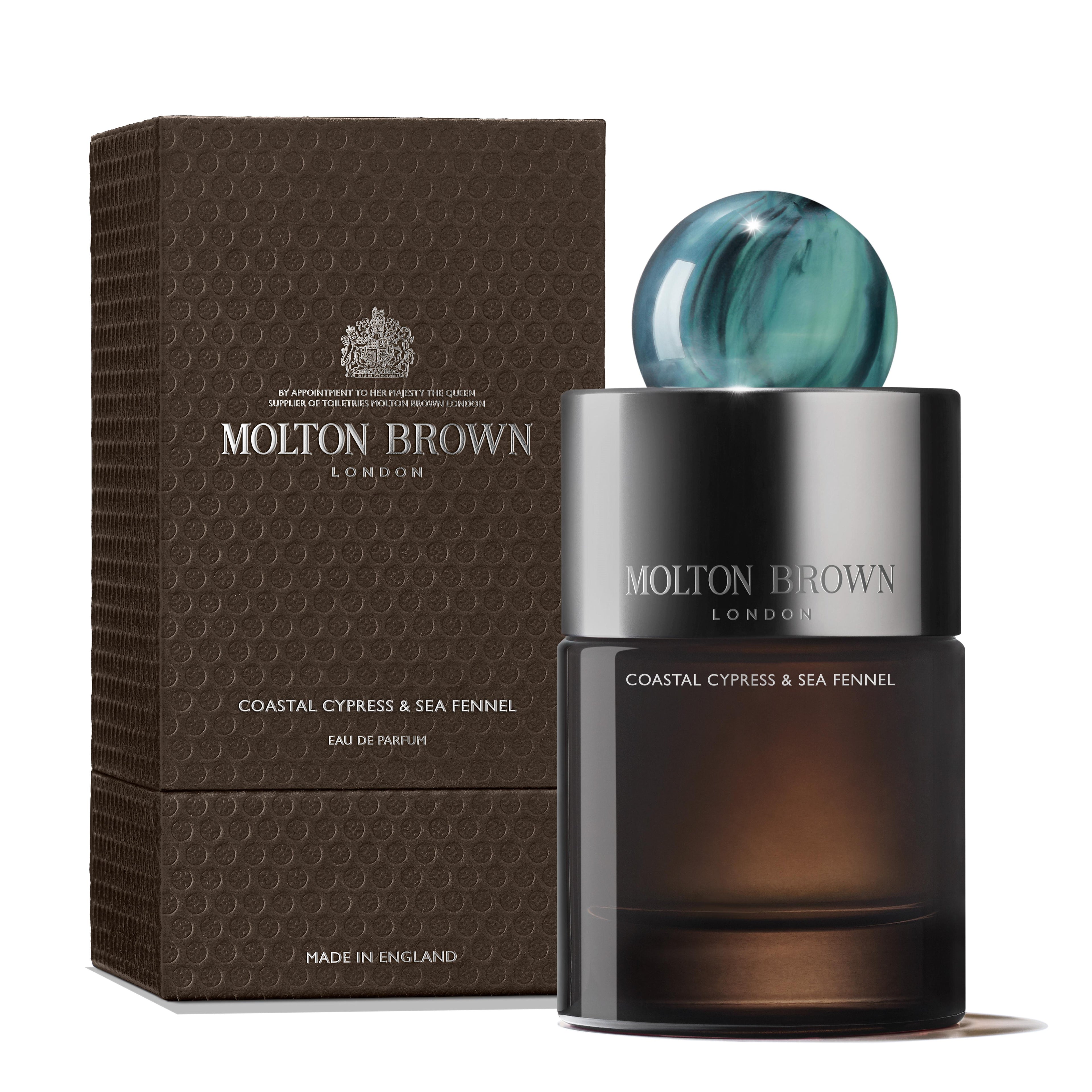 A 100ml bottle of MoltonBrown Nederlands Coastal Cypress & Sea Fennel Eau de Parfum, featuring a blue marbled cap, is displayed before its textured brown box, both labeled with the brand and fragrance name.