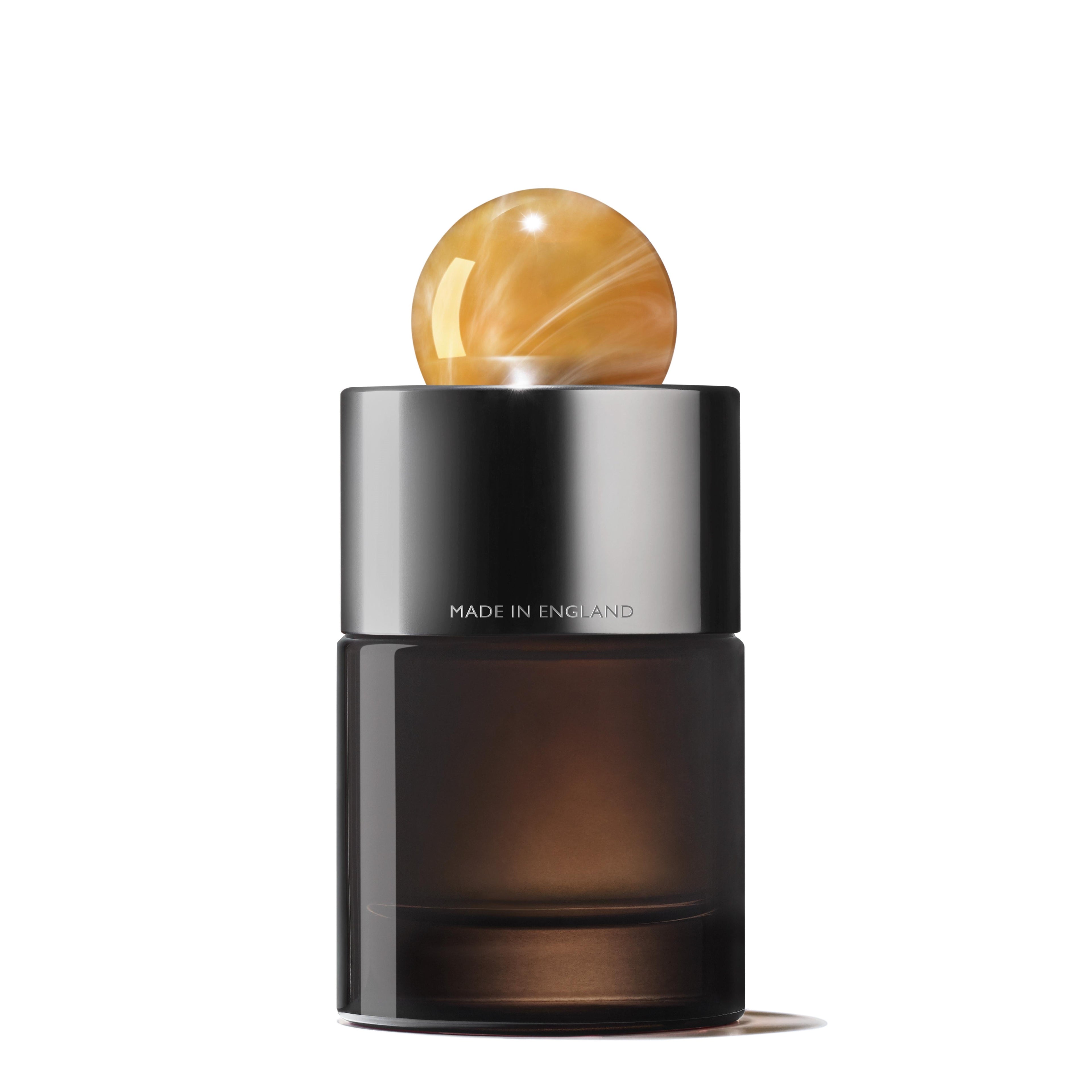 The MoltonBrown Nederlands Flora Luminare Eau de Parfum 100ml comes in a dark, cylindrical bottle with a shiny metallic cap topped by a marbled amber sphere; "MADE IN ENGLAND" is engraved on the cap.
