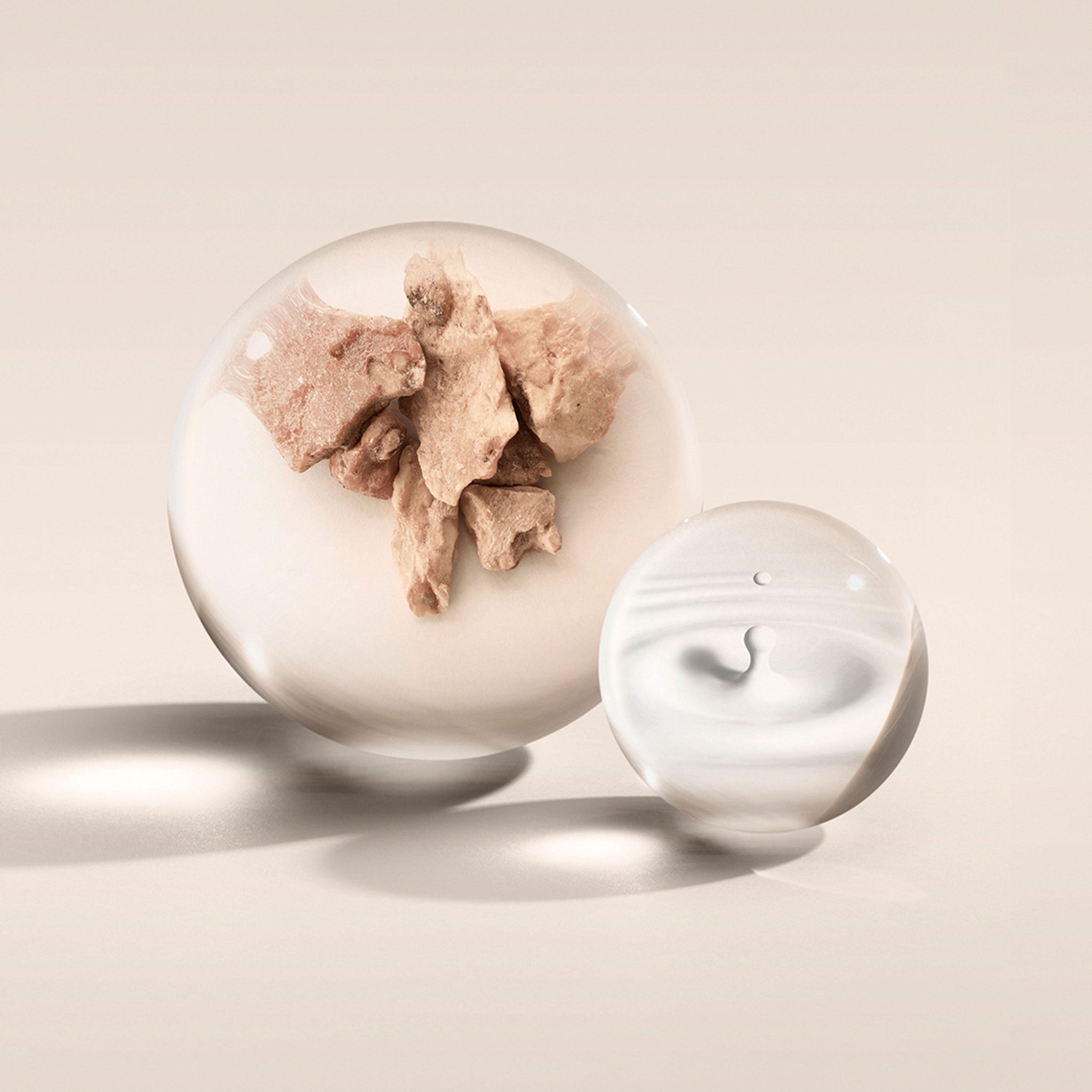 Two glass spheres on a light backdrop: the larger holds beige, vanilla-like fragments, while the smaller features a milky swirl echoing MoltonBrown Nederlands' Milk Musk Eau de Parfum 100ml. Both cast gentle shadows.