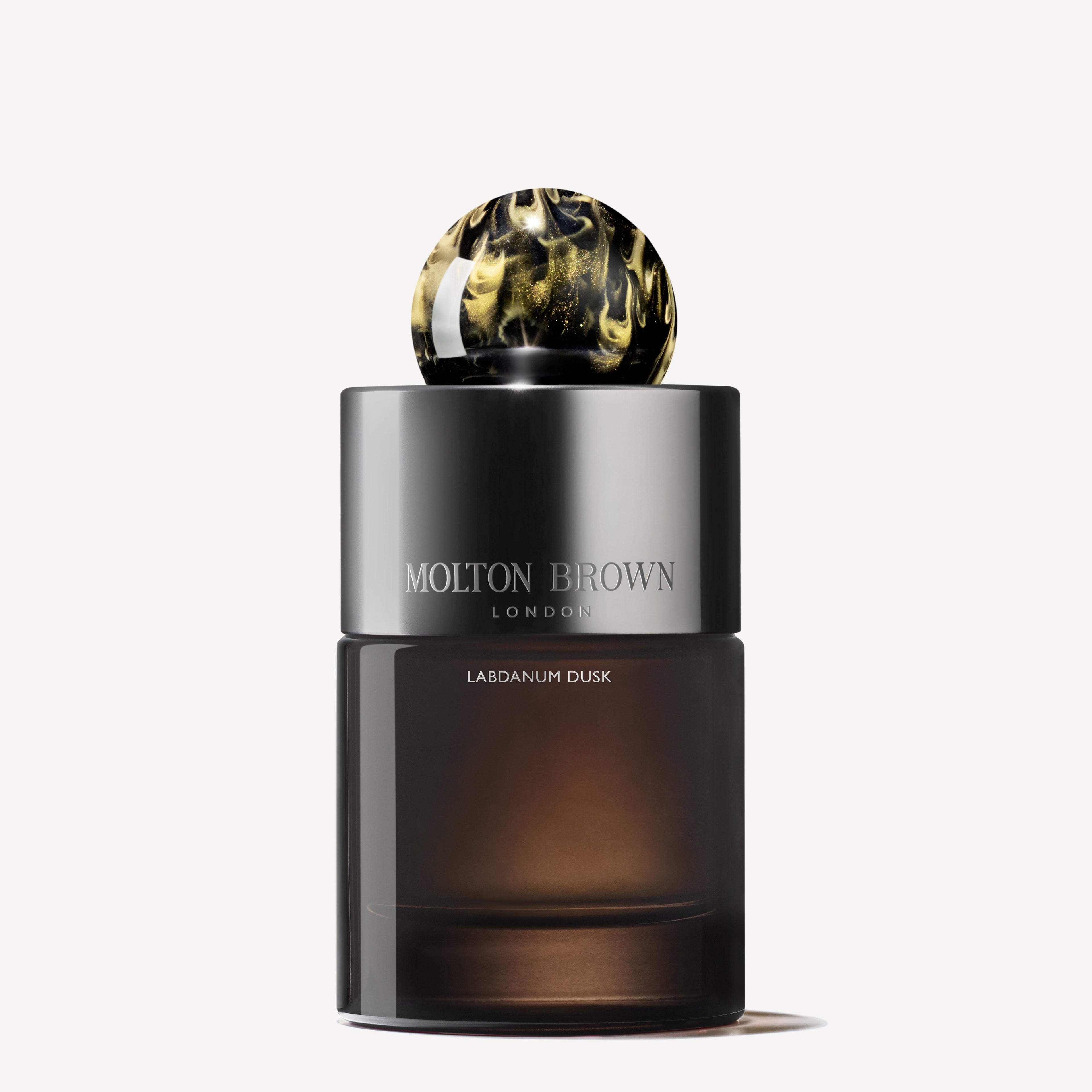 A 100ml bottle of MoltonBrown Nederlands Labdanum Dusk Eau de Parfum, with a dark gradient glass design and a round, marbled black and gold cap, displayed against a plain white background.