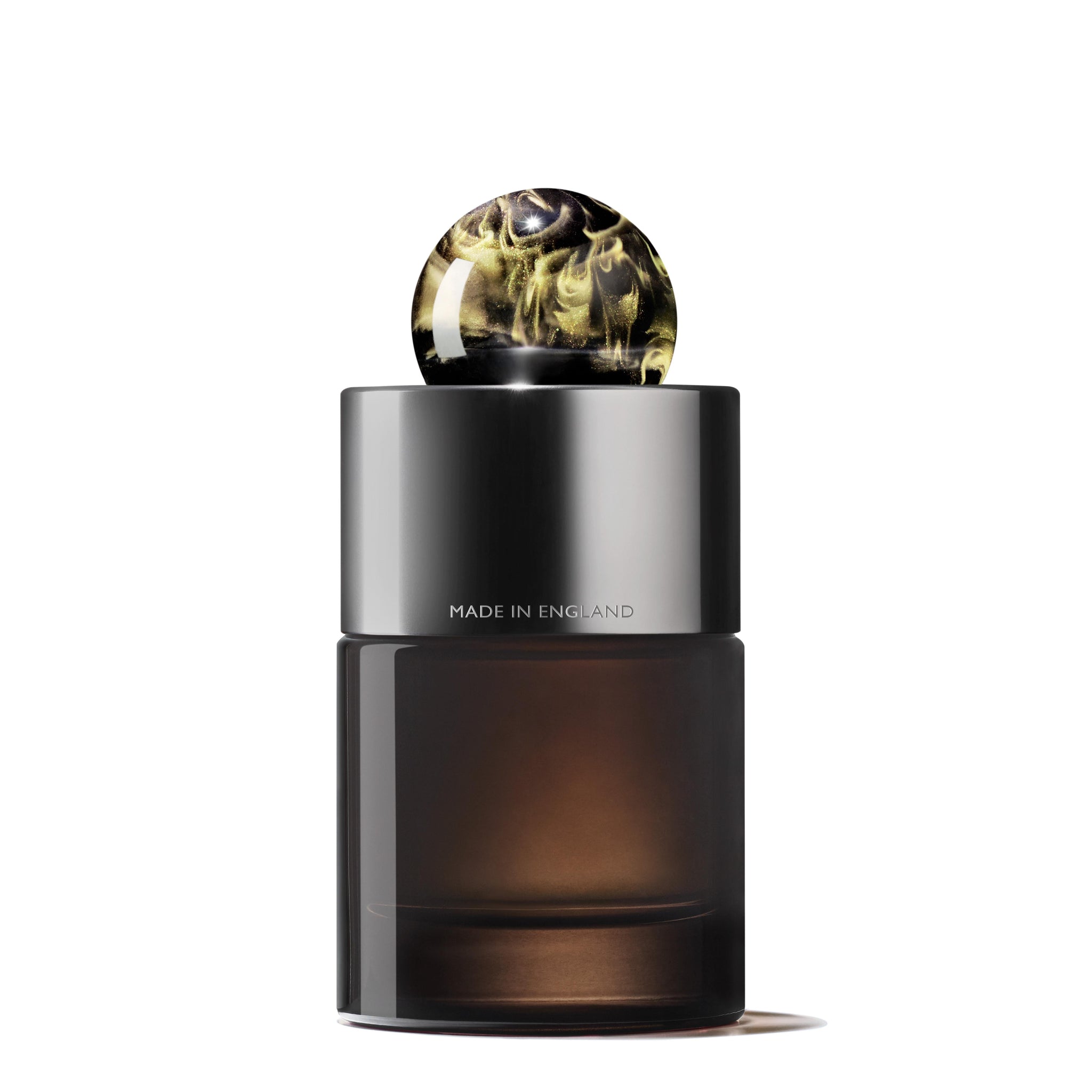 The MoltonBrown Nederlands Labdanum Dusk Eau de Parfum 100ml features a sleek dark glass bottle with a metallic cap and black-gold marbled spherical top. "Made in England" is printed on it. Neroli notes inspire its elegant design, set against a white background.