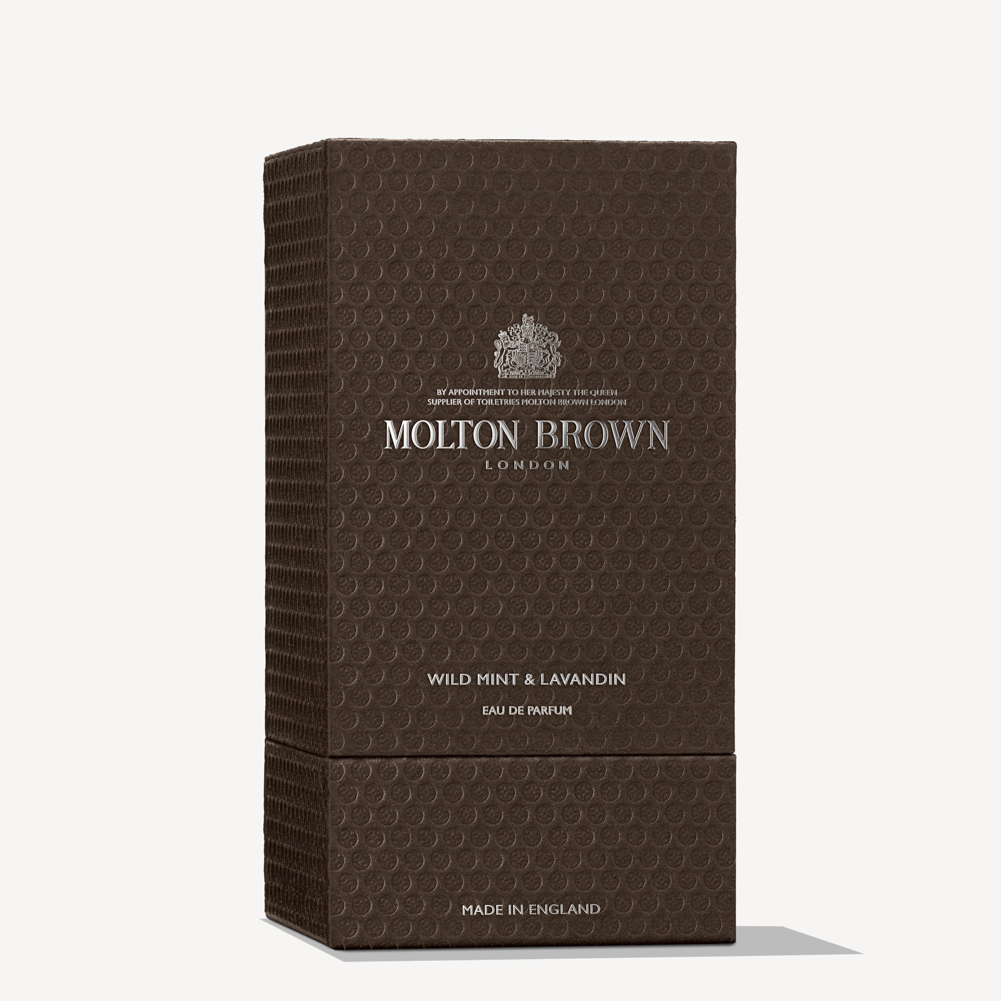 A tall, rectangular, textured brown box from MoltonBrown Nederlands features silver text with "Wild Mint & Lavandin Eau de Parfum 100ml" and hints at lavender and white floral notes. "Made in England" appears at the bottom.