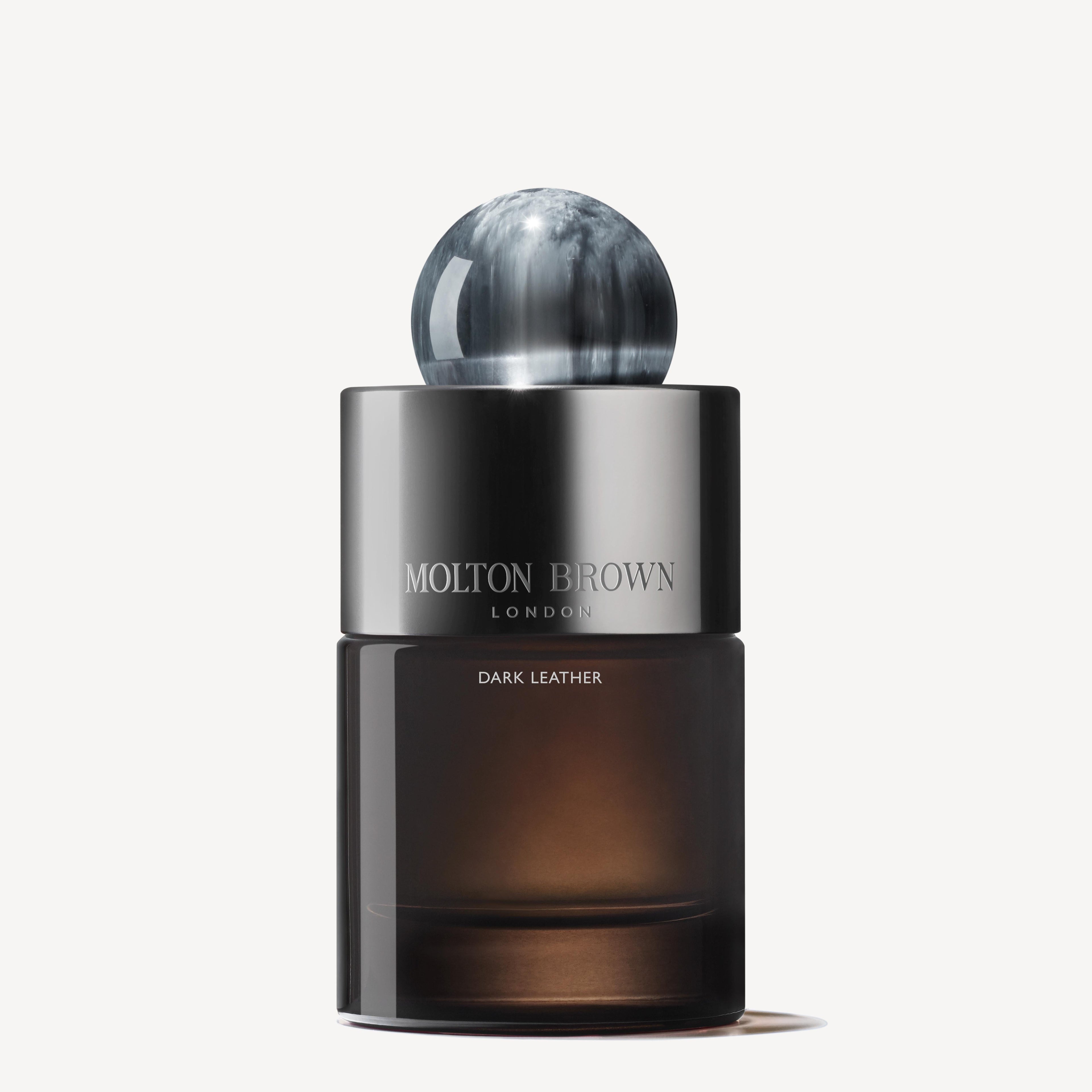 A 100ml bottle of MoltonBrown Nederlands Dark Leather Eau de Parfum, featuring a smoky base, silver band, and marbled black-and-white cap, is set against a white background. Subtle musky notes linger in the air.