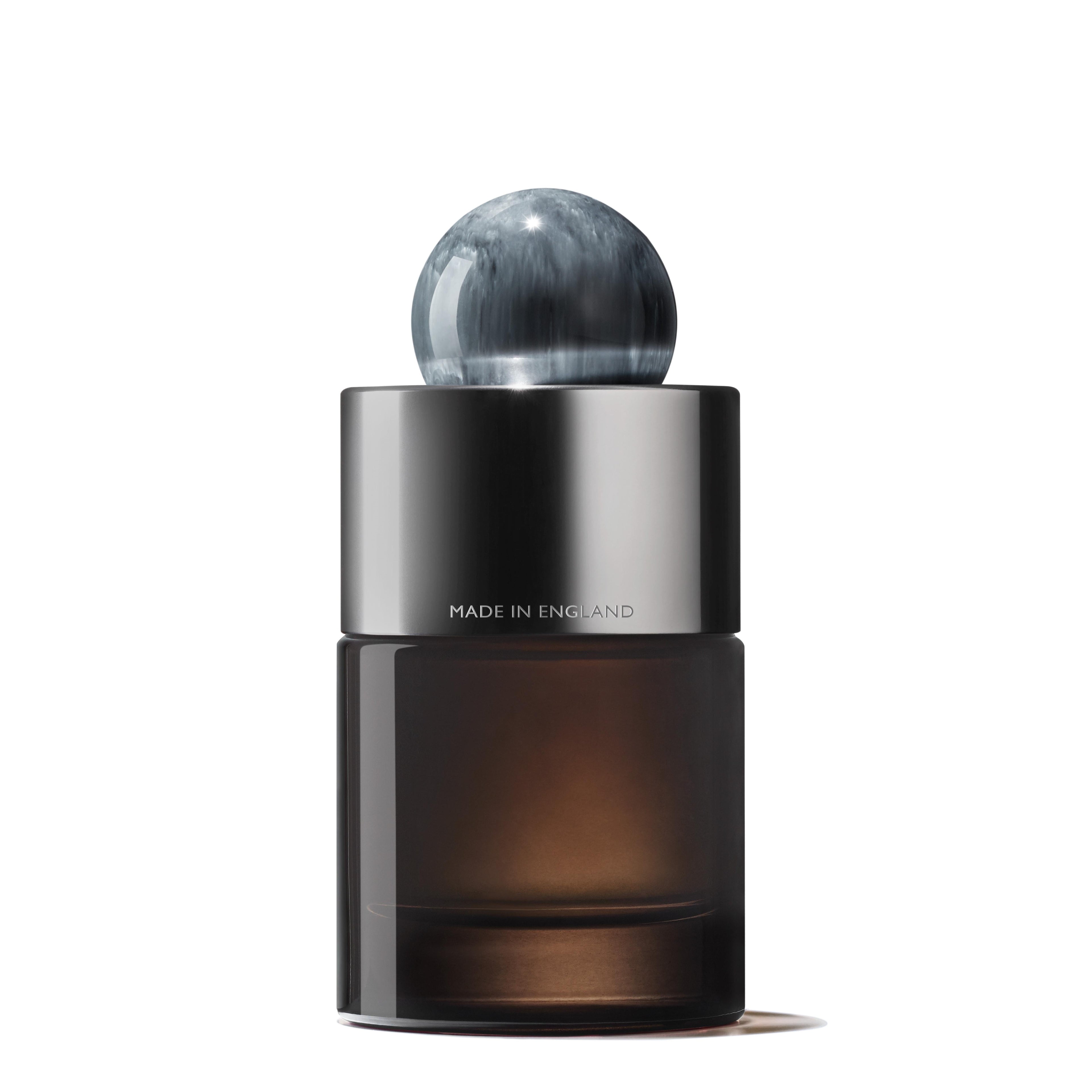A sleek, dark glass bottle of MoltonBrown Nederlands Dark Leather Eau de Parfum 100ml features a metallic band engraved with MADE IN ENGLAND and a round marbled gray cap, set against a white background.