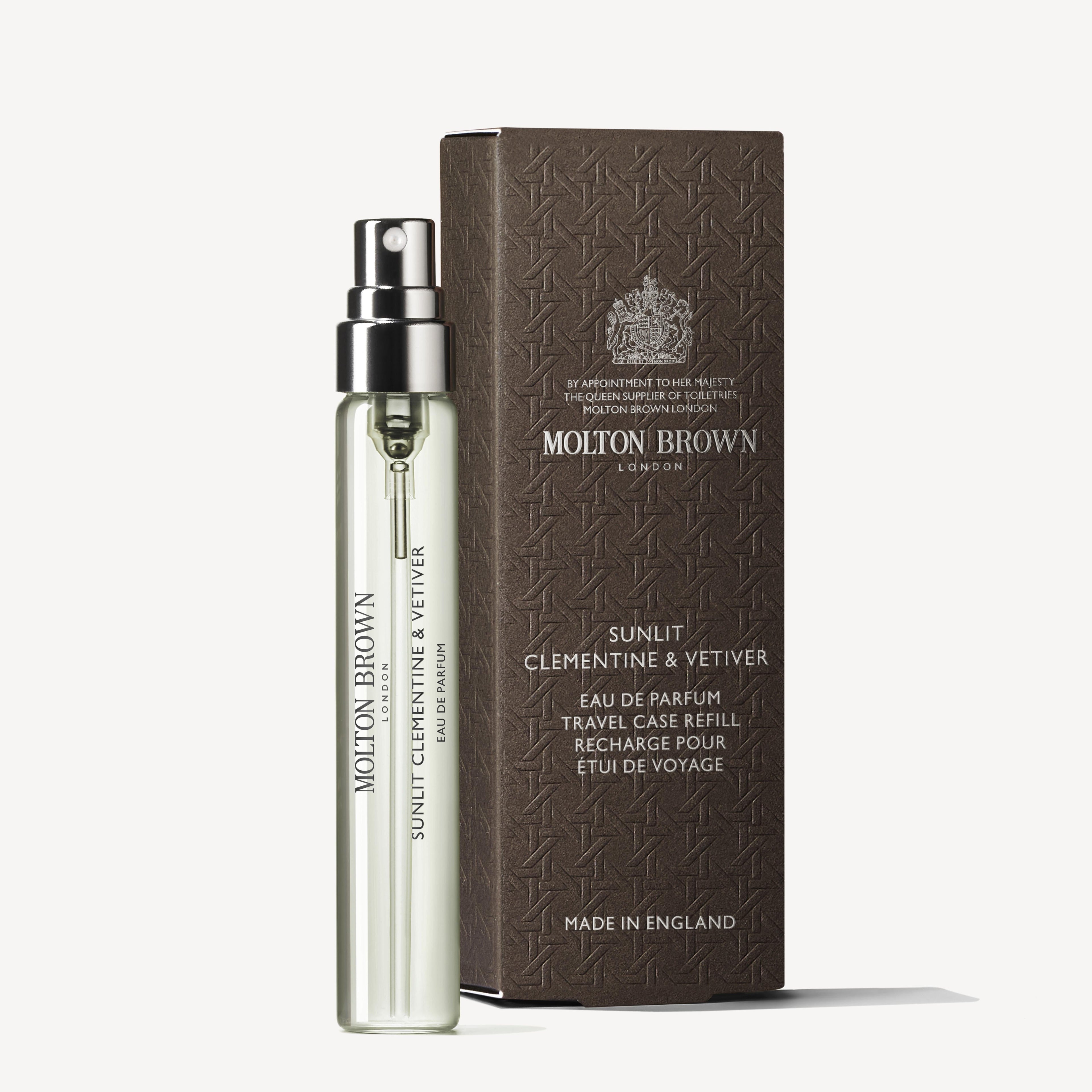 A clear MoltonBrown Nederlands Sunlit Clementine & Vetiver Bodylotion 300ml stands beside a brown textured box with matching text on a white background, evoking fresh clementine notes perfect for daily hydration.