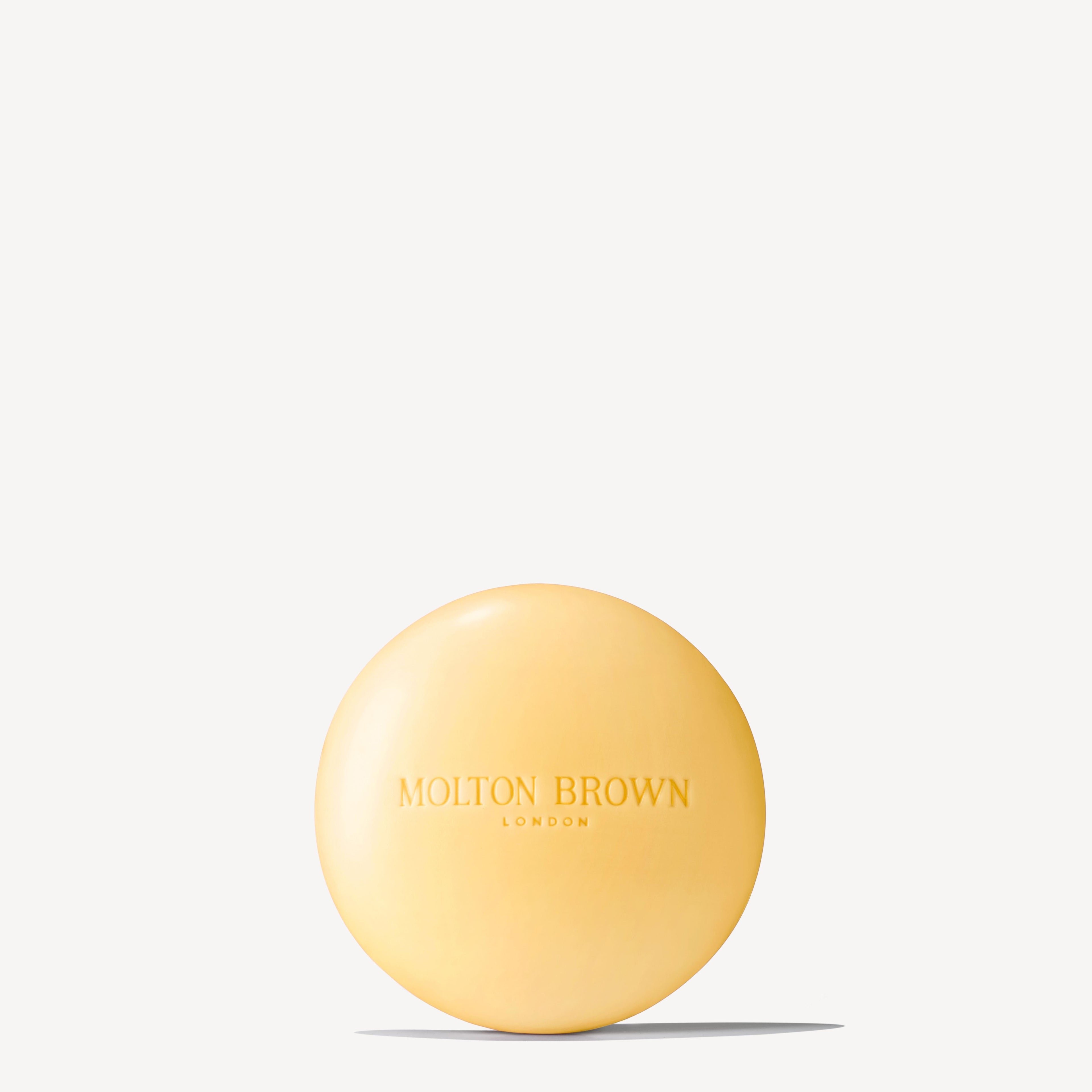A round, yellow Orange & Bergamot Perfumed Soap 150g by MoltonBrown Nederlands, enriched with natuurlijke oliën and embossed with the brand name on the front, shown against a plain white background.