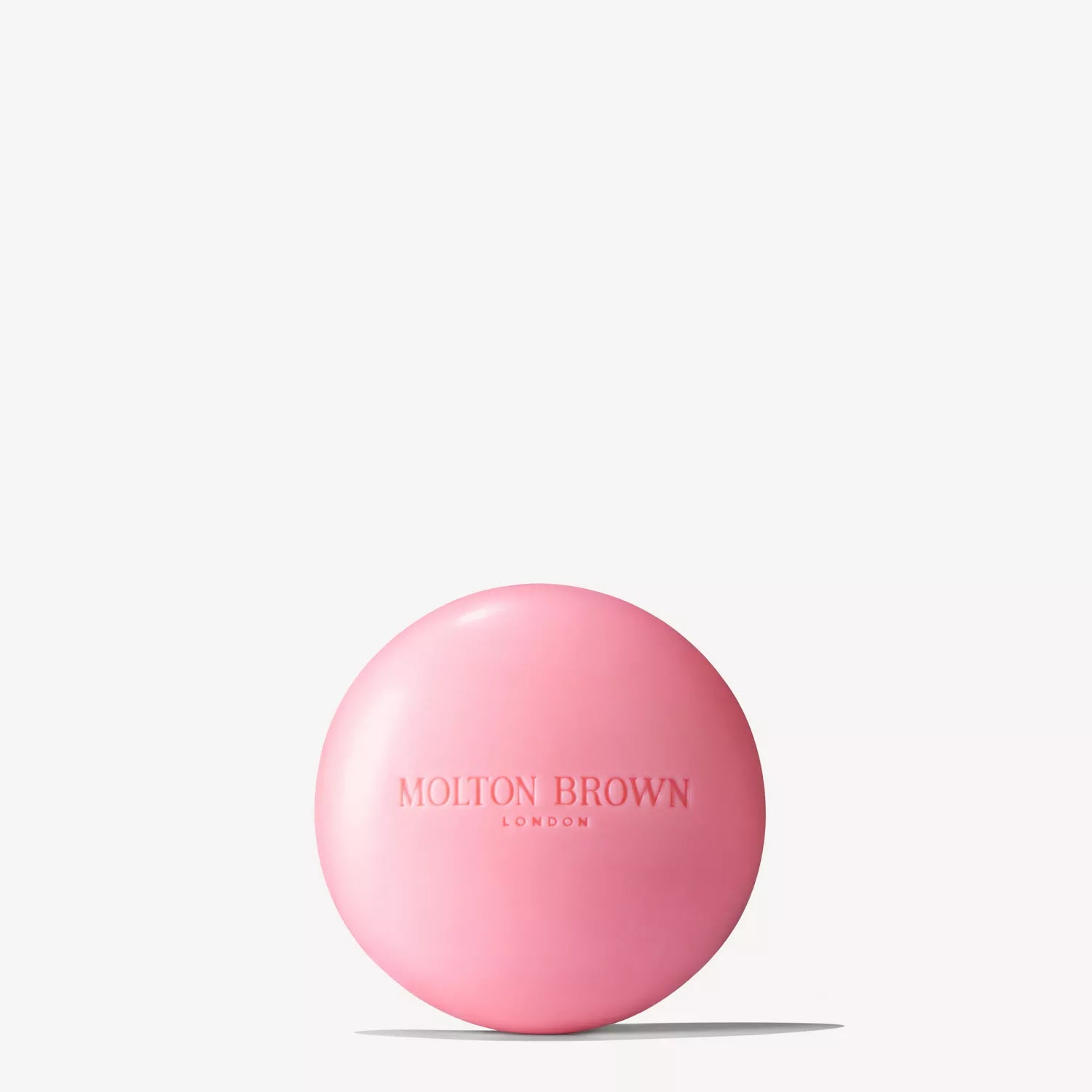 A round, pink Fiery Pink Pepper Perfumed Soap 150g by MoltonBrown Nederlands, embossed with the brand name and enriched with sheaboter, is shown against a plain white background.