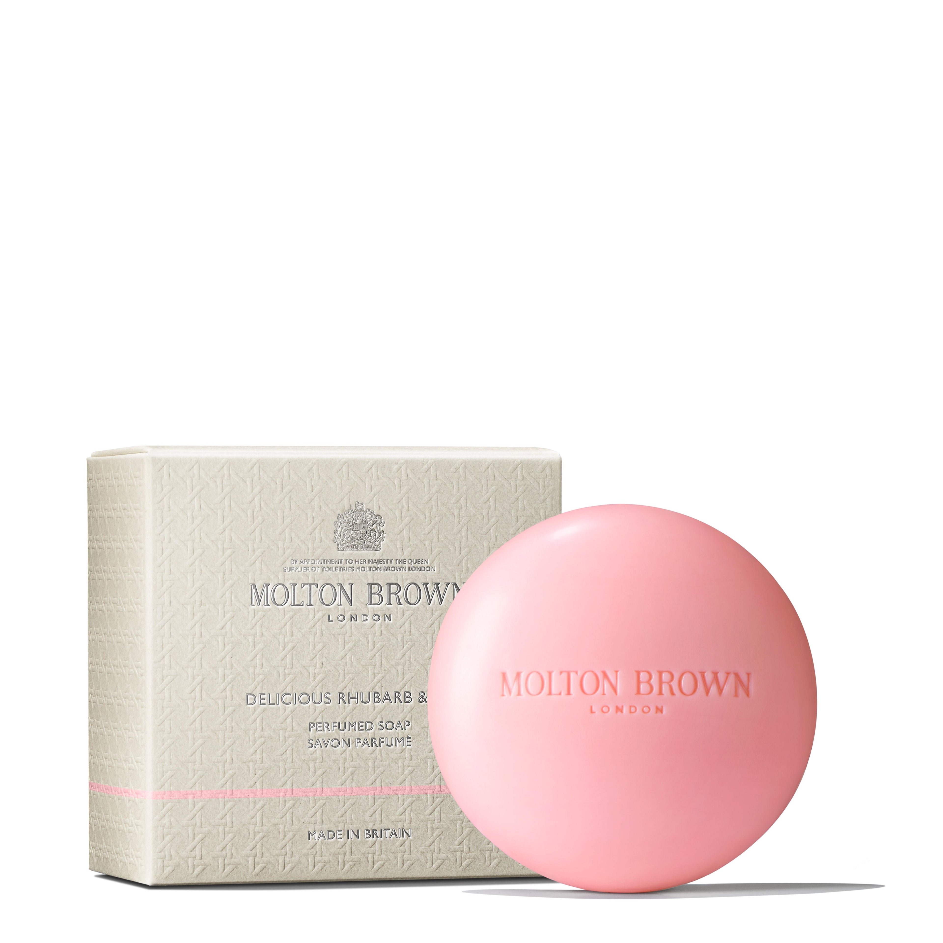 A round, pale pink MoltonBrown Nederlands soap sits before its cream-toned box labeled Delicious Rhubarb & Rose Perfumed Soap, evoking the scent of Rose Dunes Bodylotion 300ml with Bulgarian rose and amber-rose notes.