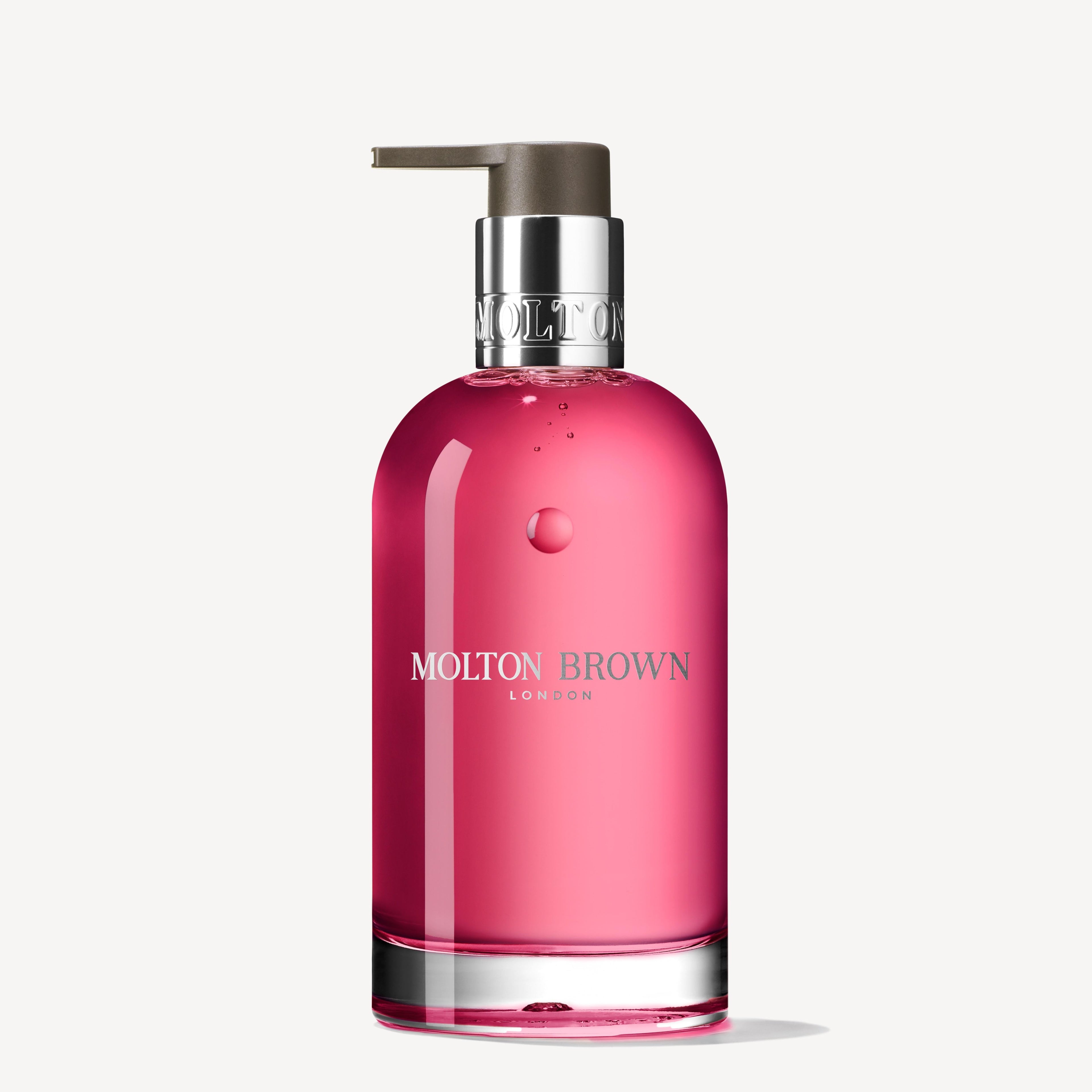 A clear glass pump bottle with pink liquid, labeled “MoltonBrown Nederlands,” contains Fiery Pink Pepper Vloeibare Handzeep Glazen Fles 200ml, a houtig-kruidig hand soap with notes of patchouli and roze peper, set against a white background.
