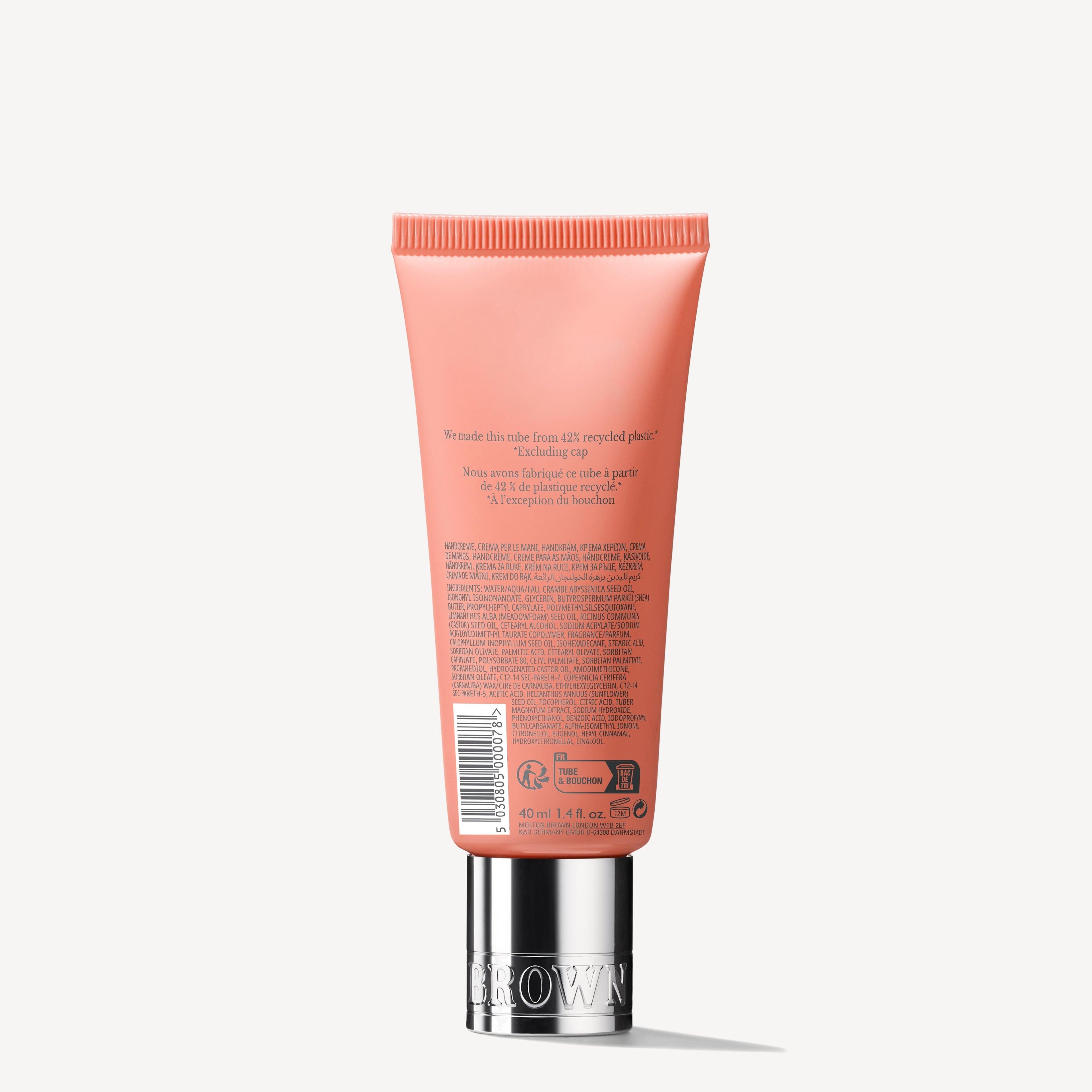 A coral-colored tube of MoltonBrown Nederlands Heavenly Gingerlily Handcrème 40ml with shea butter and a silver cap is shown from the back, displaying product details against a plain white background.