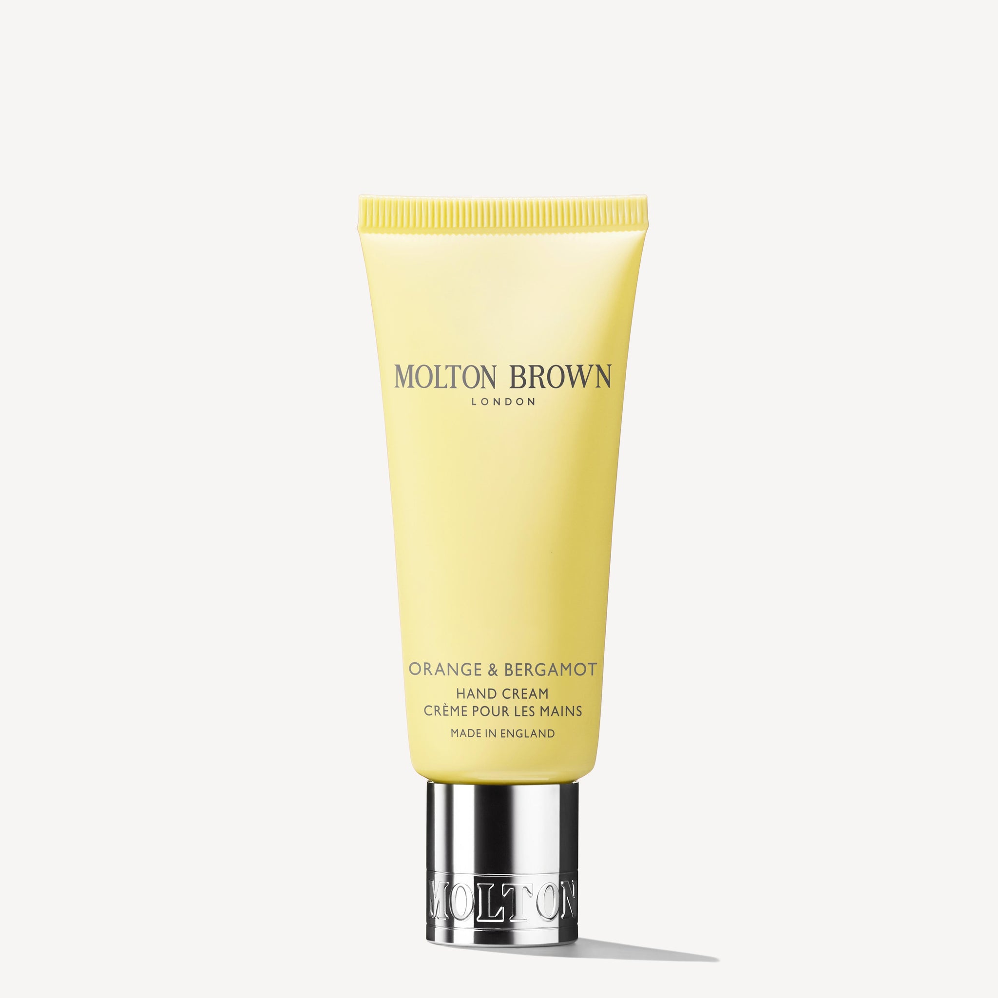 A yellow tube of MoltonBrown Nederlands Orange & Bergamot Handcrème 40ml with sheabutter and a silver cap stands upright against a white background.