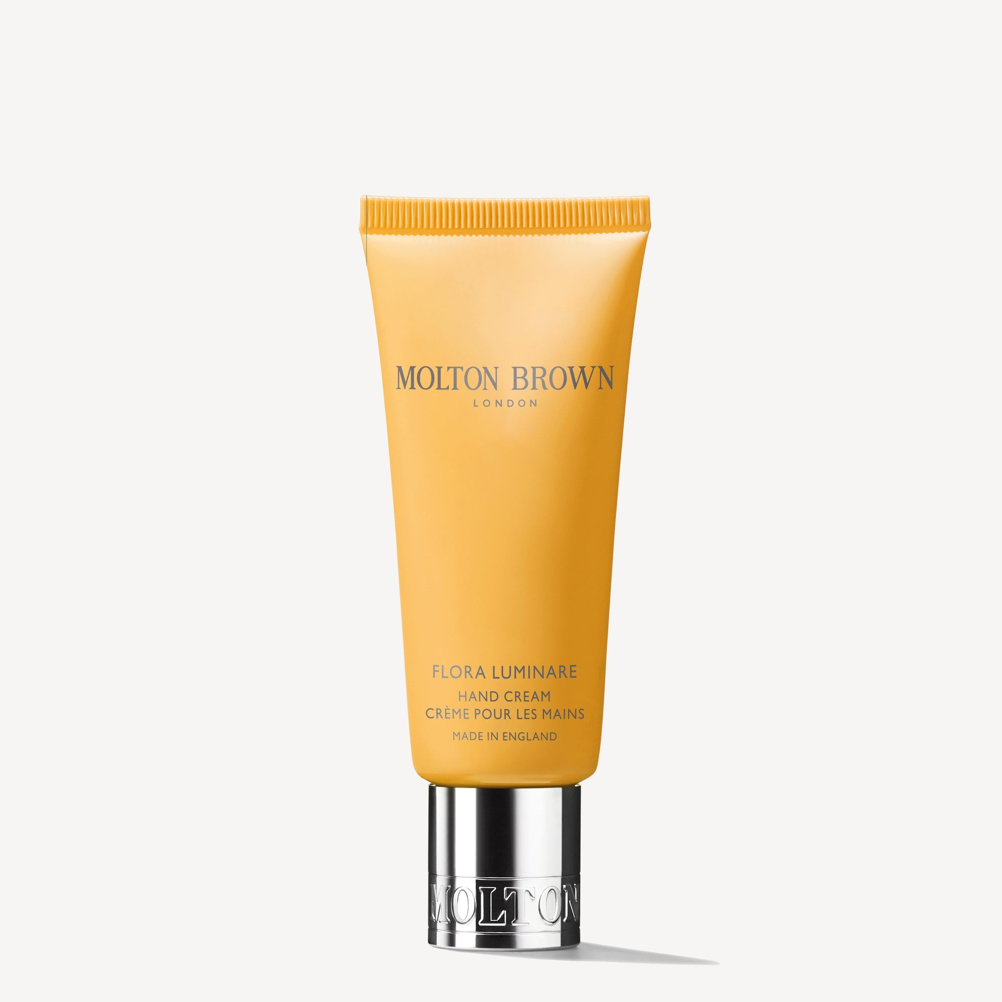 A yellow 40ml tube of MoltonBrown Nederlands Flora Luminare Handcrème with sheaboter and a silver cap, standing upright against a plain white background.
