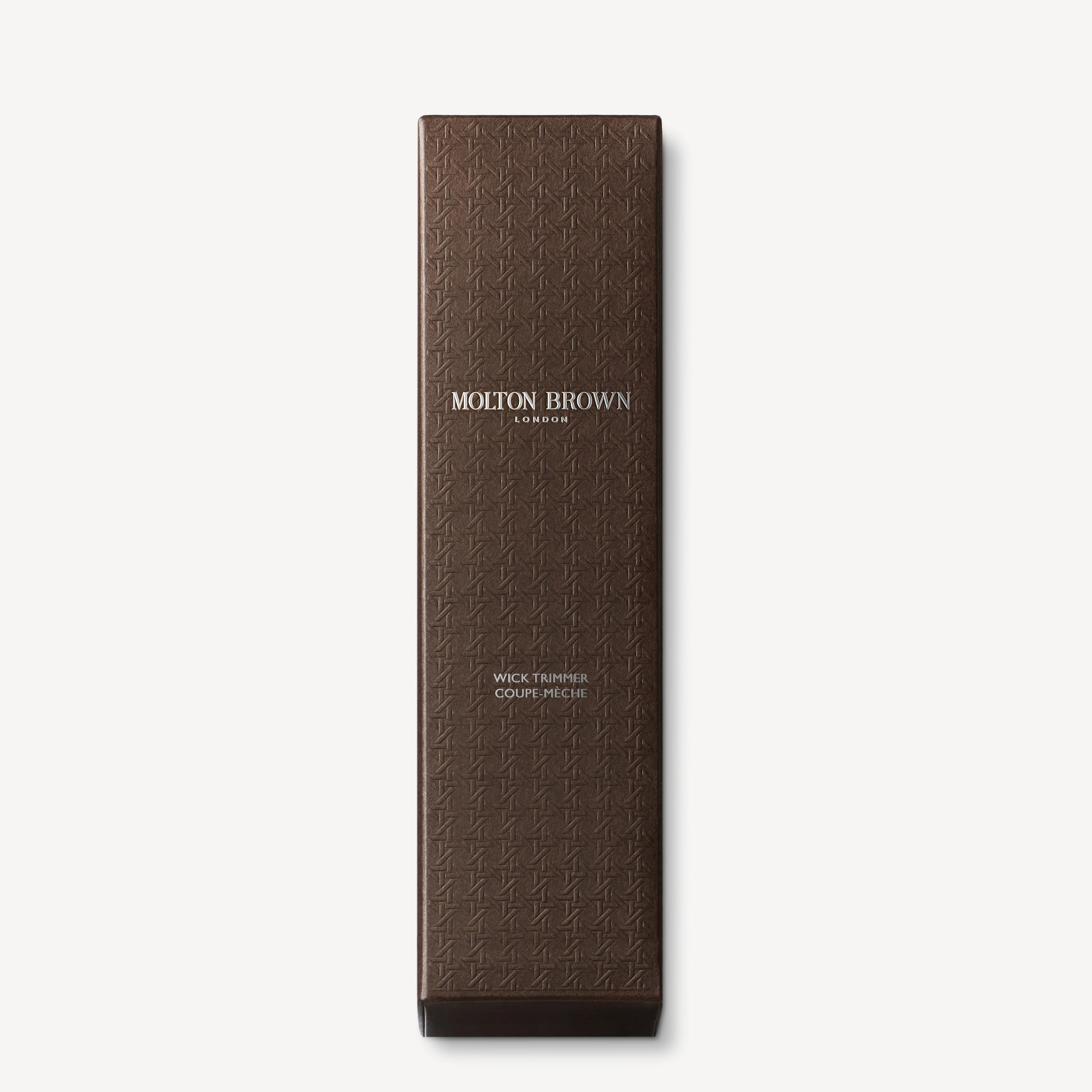 A rectangular brown box with a textured pattern and white text reading MoltonBrown Nederlands and Wick Trimmer 72g—this stylish kaarsaccessoire is shown against a white background.