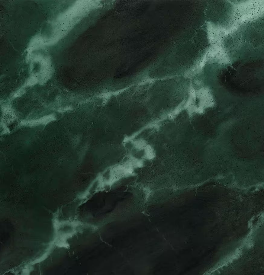 A close-up view of a dark green marble surface with lighter green and white veins running across it, creating a natural, textured pattern.